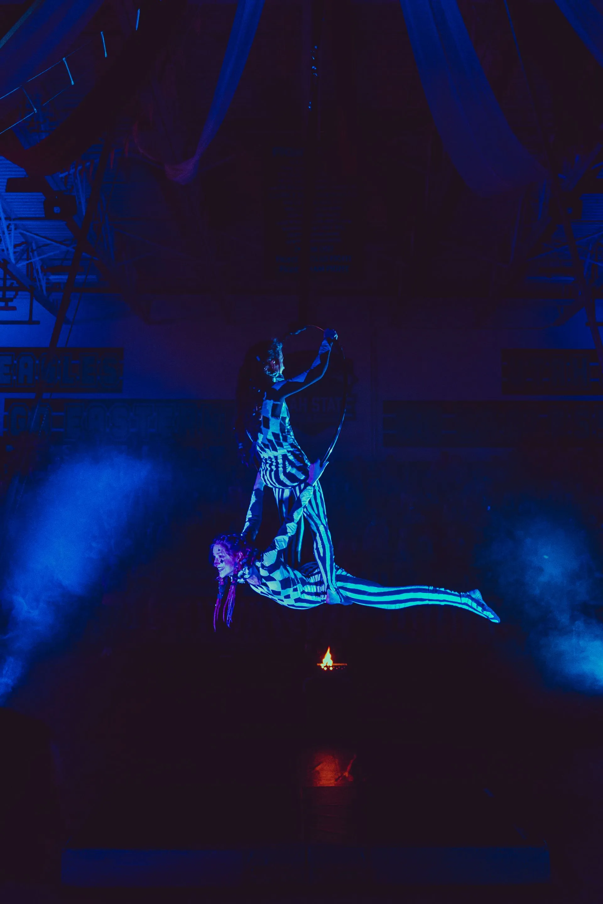 A man and a woman are flying through the air in a dark room.