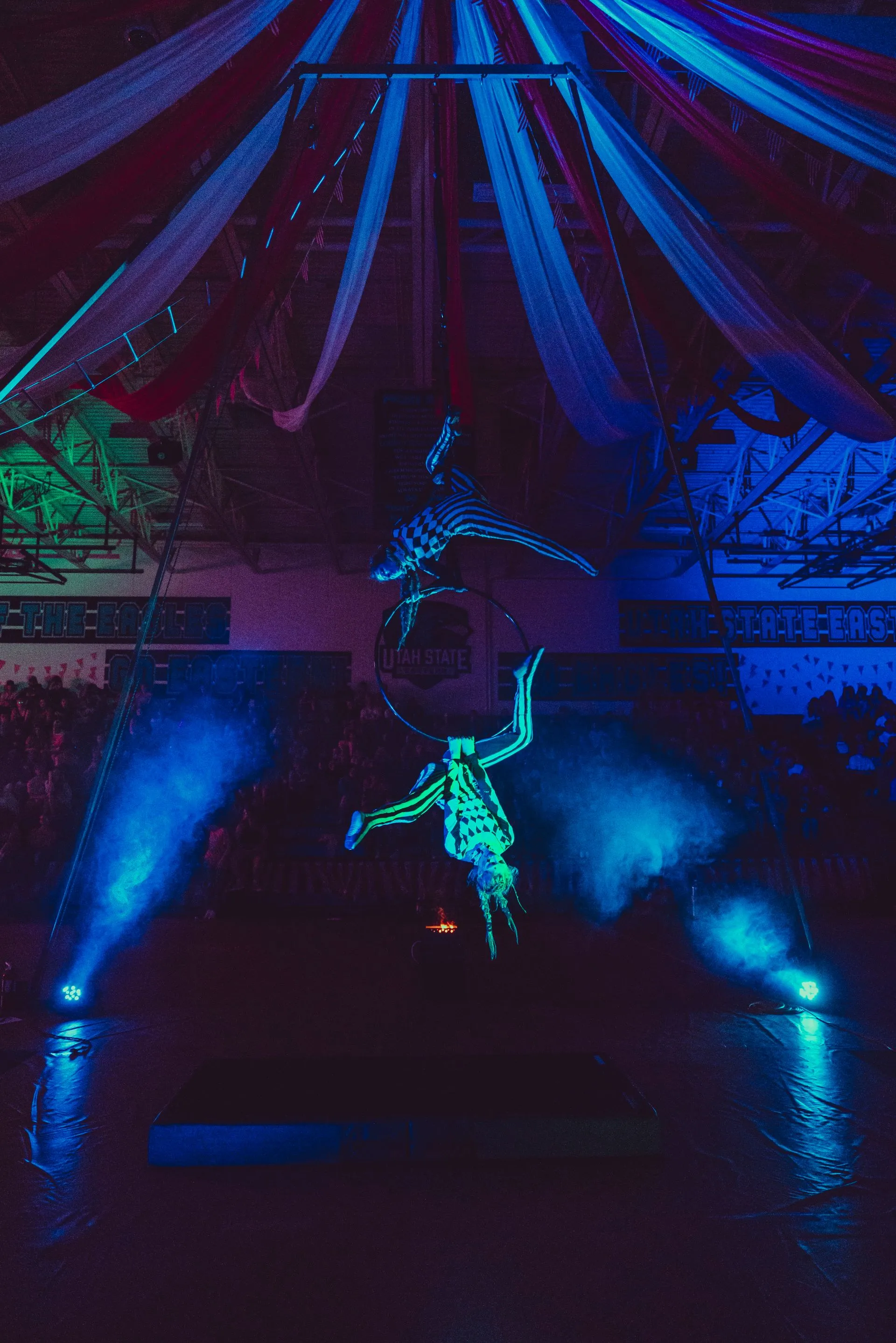A group of people are performing aerial acrobatics in a dark room.