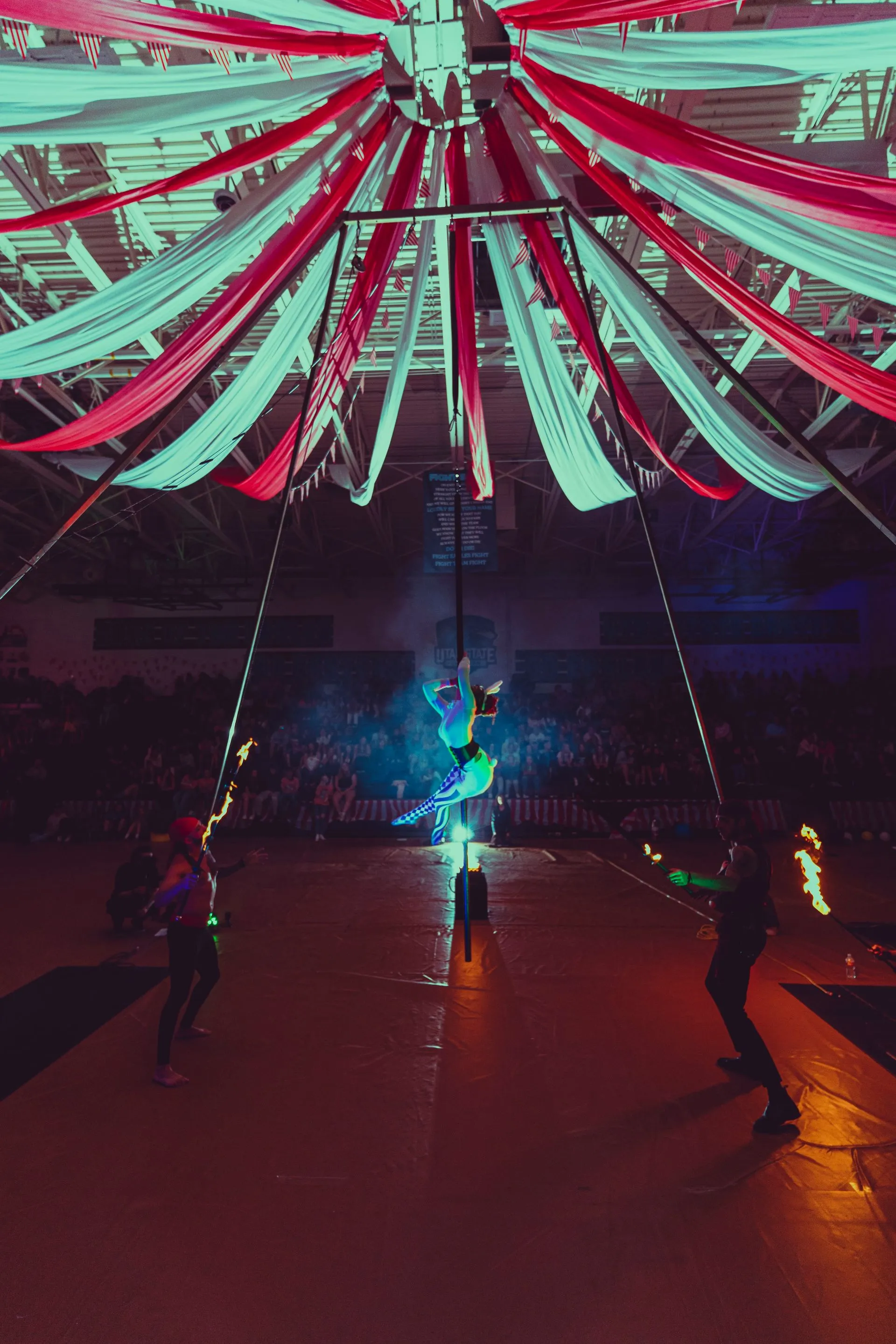 A group of people are performing aerial acrobatics in a gym.