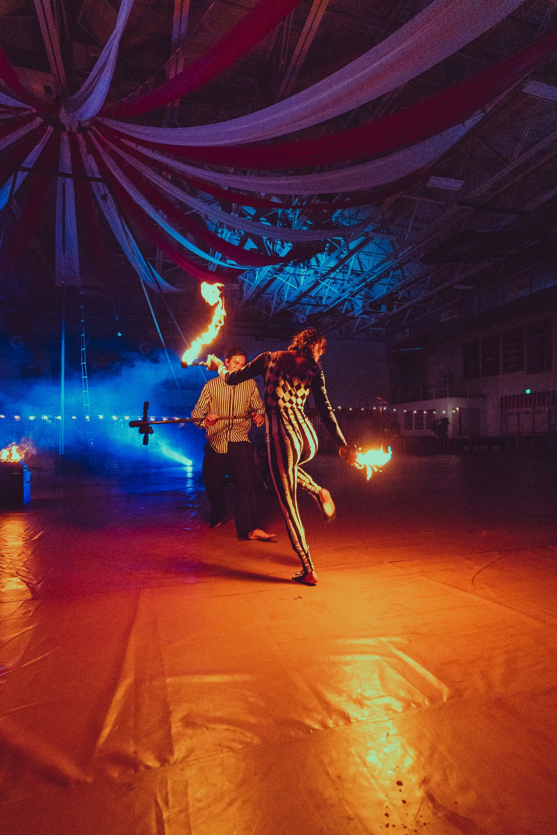 A group of people are dancing with fire in a dark room.