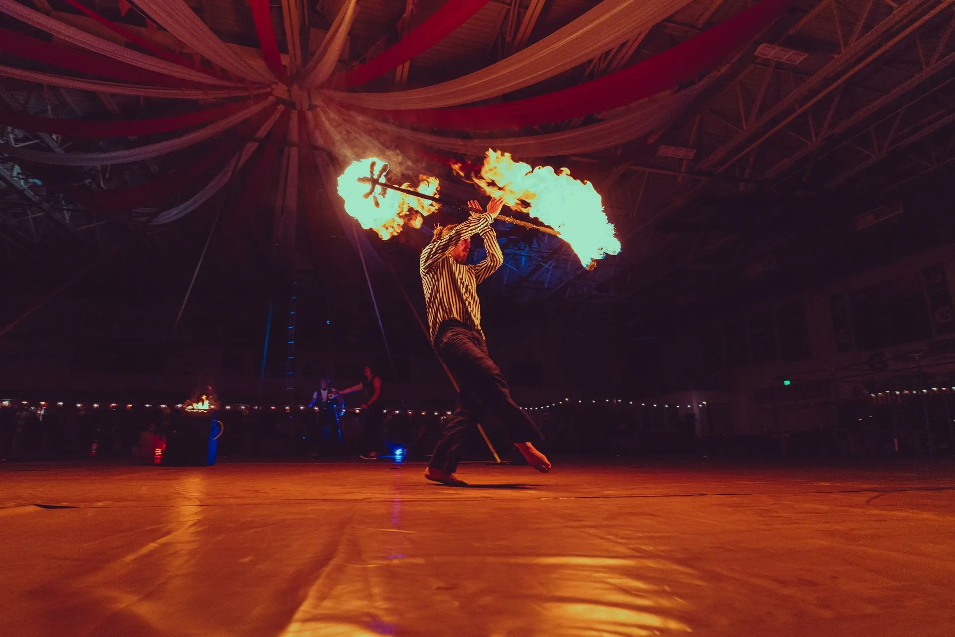 A man is holding a stick of fire in a dark room.