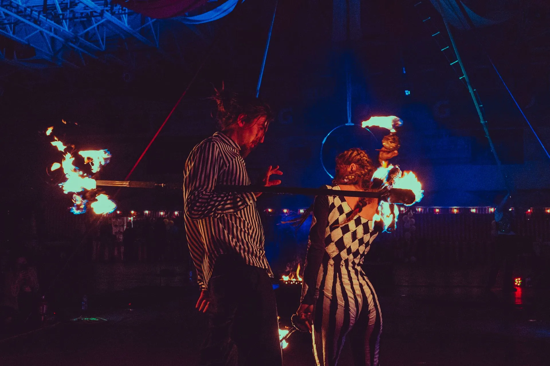 A man and a woman are holding fire sticks in a dark room.