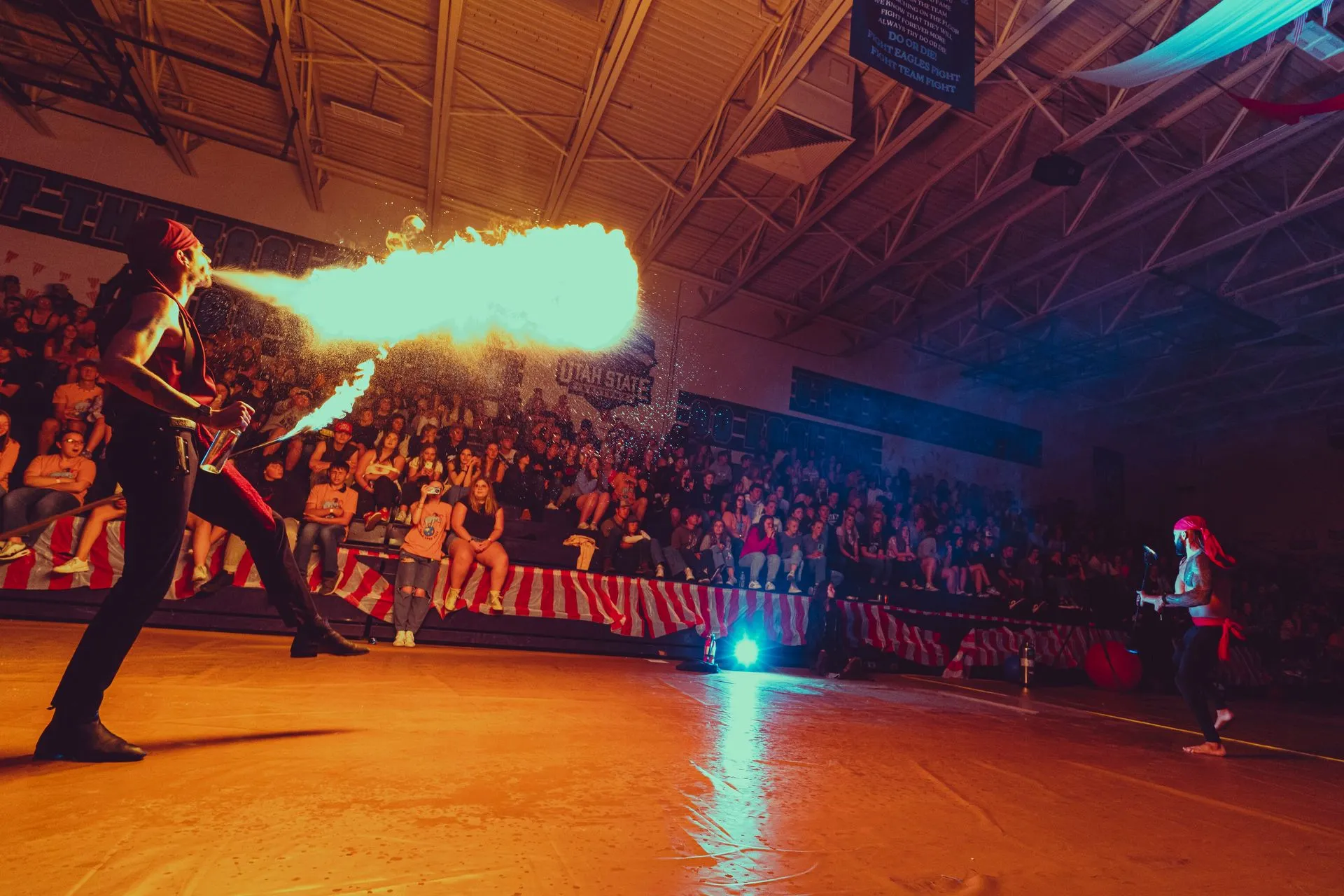 A man is holding a fireball in his mouth in front of a crowd.