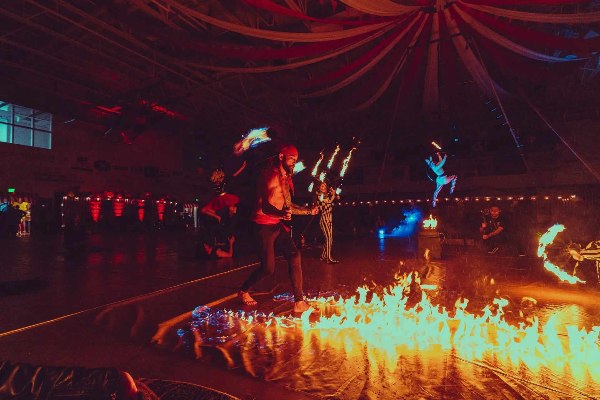 A group of people are performing a fire show in a dark room.