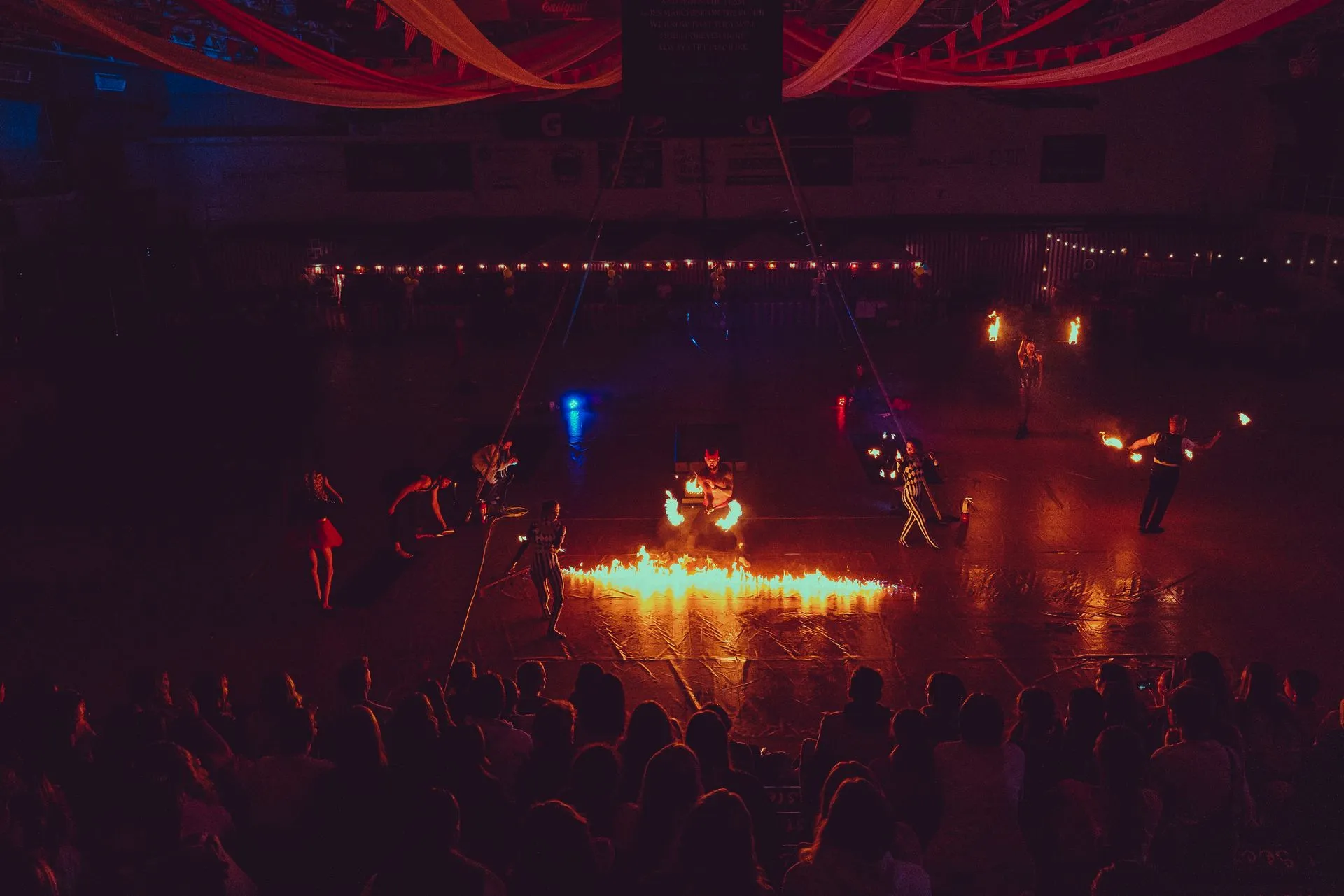 A crowd of people are watching a fire show in a stadium.