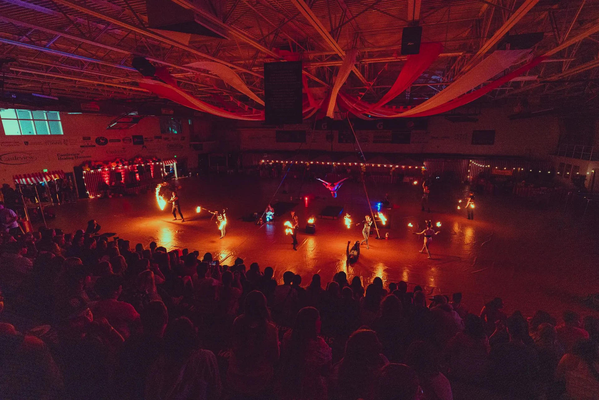 A large crowd of people are watching a fire show in a stadium.