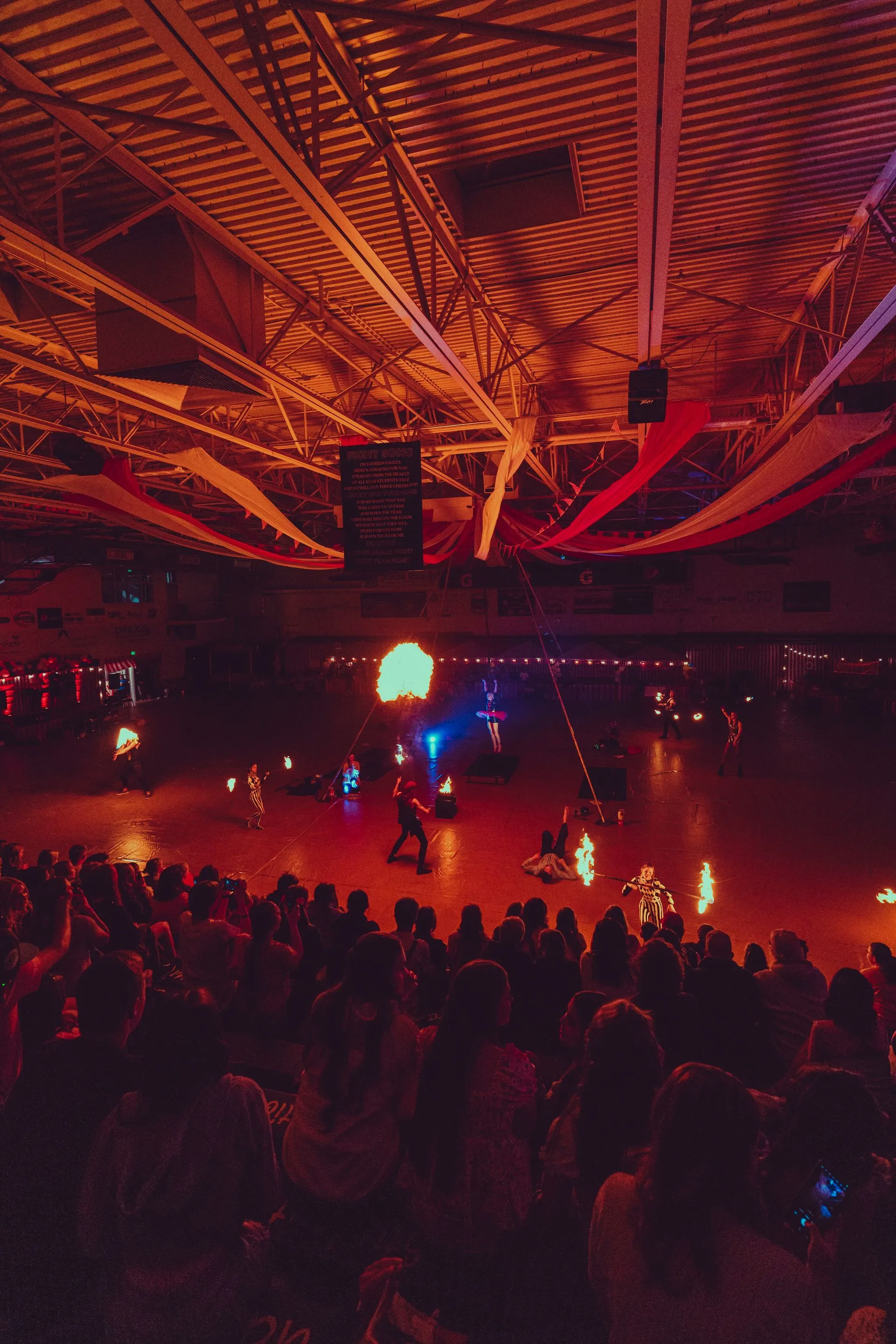 A crowd of people are watching a fire show in a stadium.