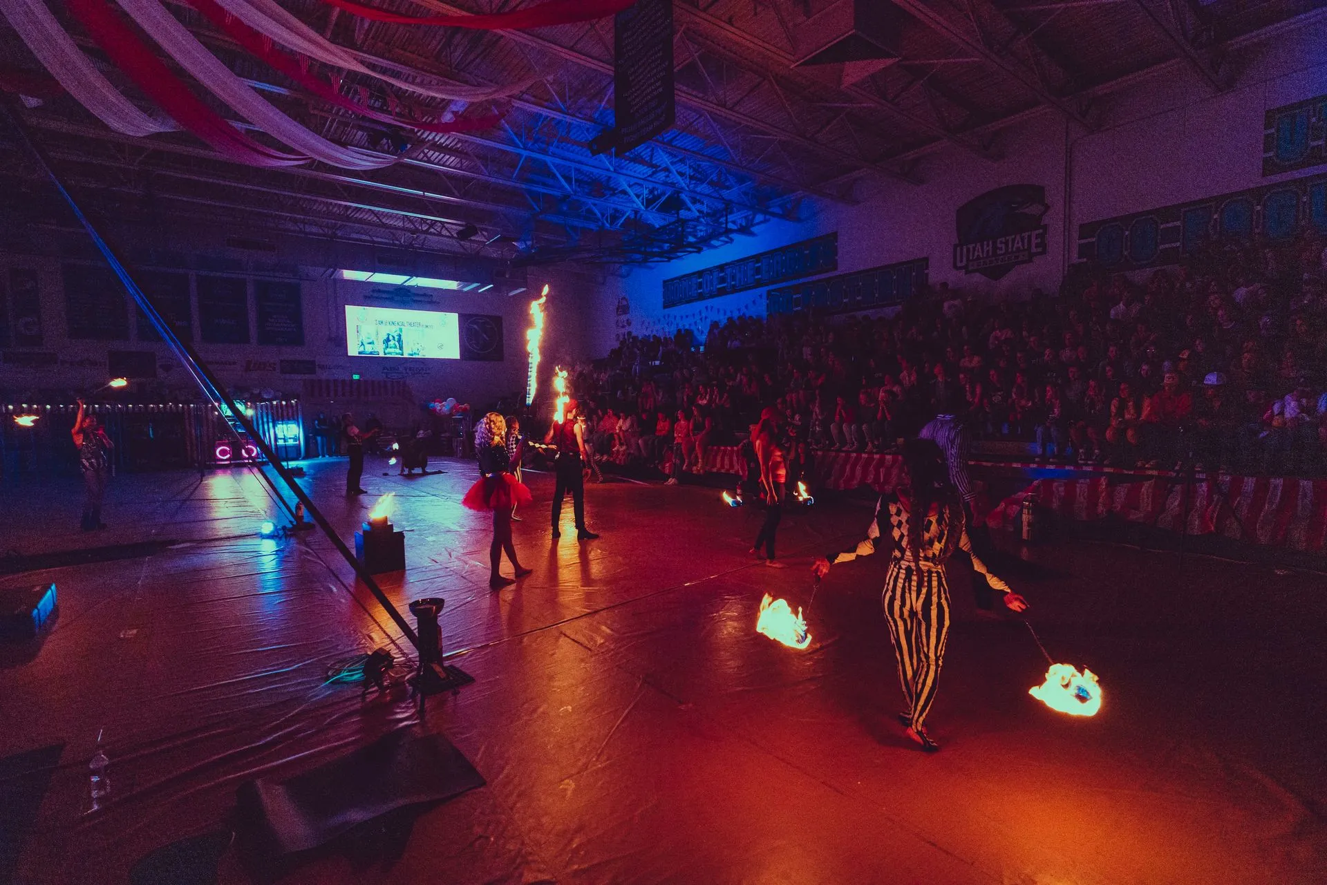 A group of people are dancing with fire in a gym.