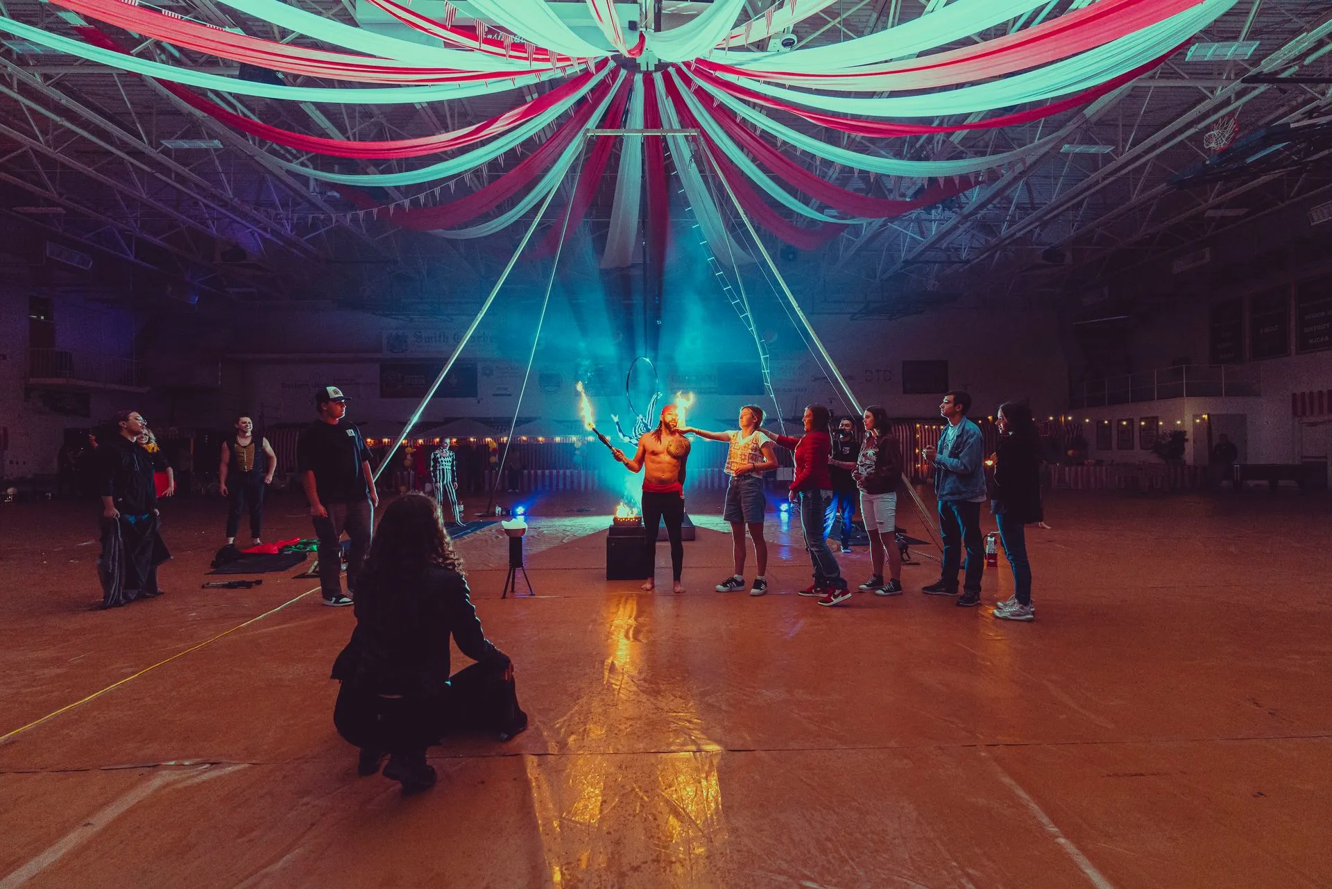 A group of people are standing in a large room holding torches.