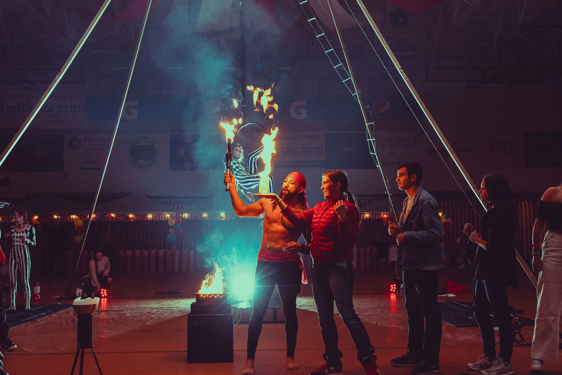 A group of people are standing around a man holding a fire torch.