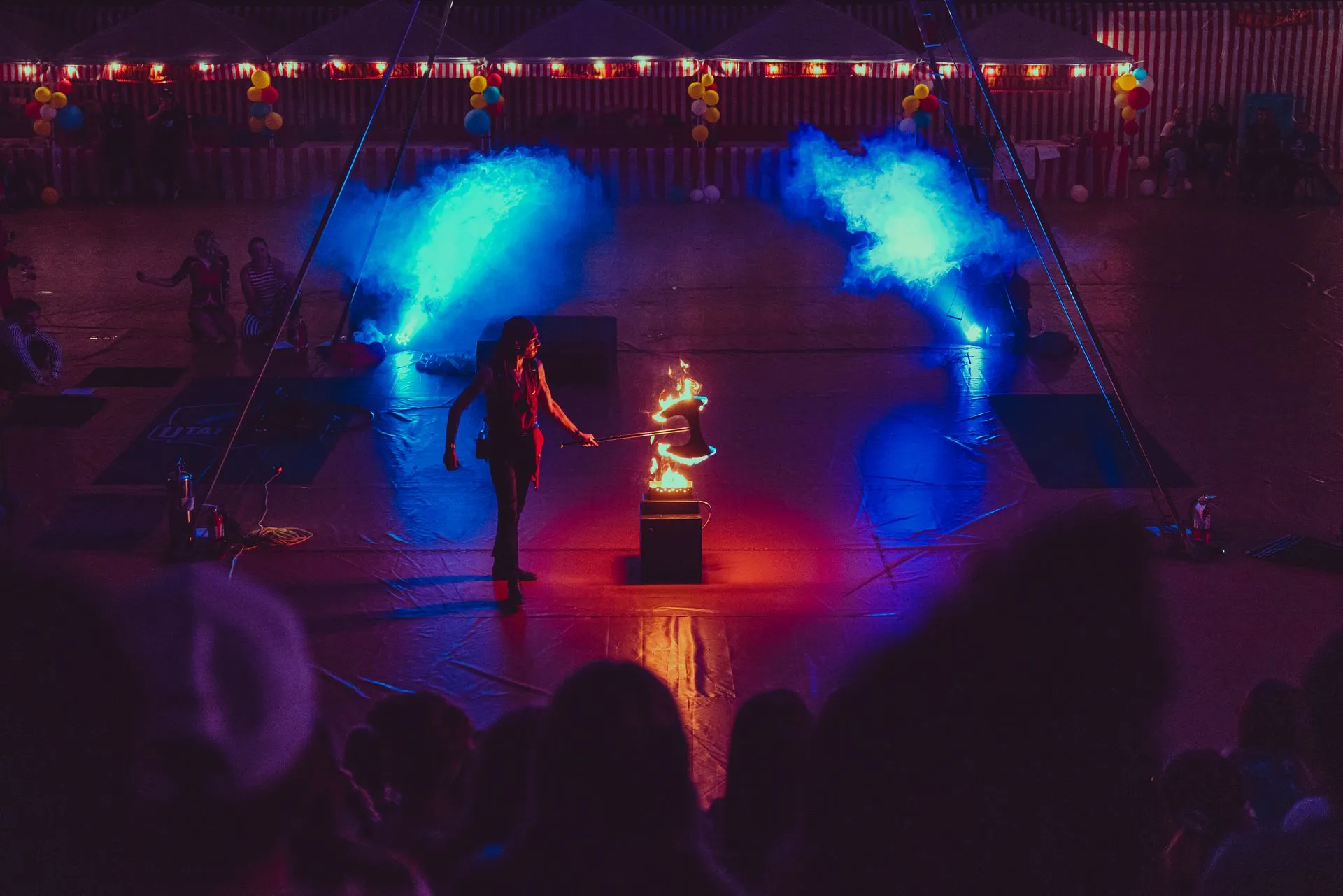 A woman is standing on a stage holding a torch in front of a crowd.