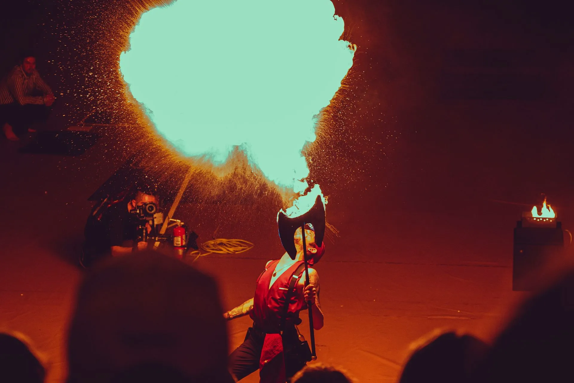 A woman in a red dress is blowing fire out of her mouth.