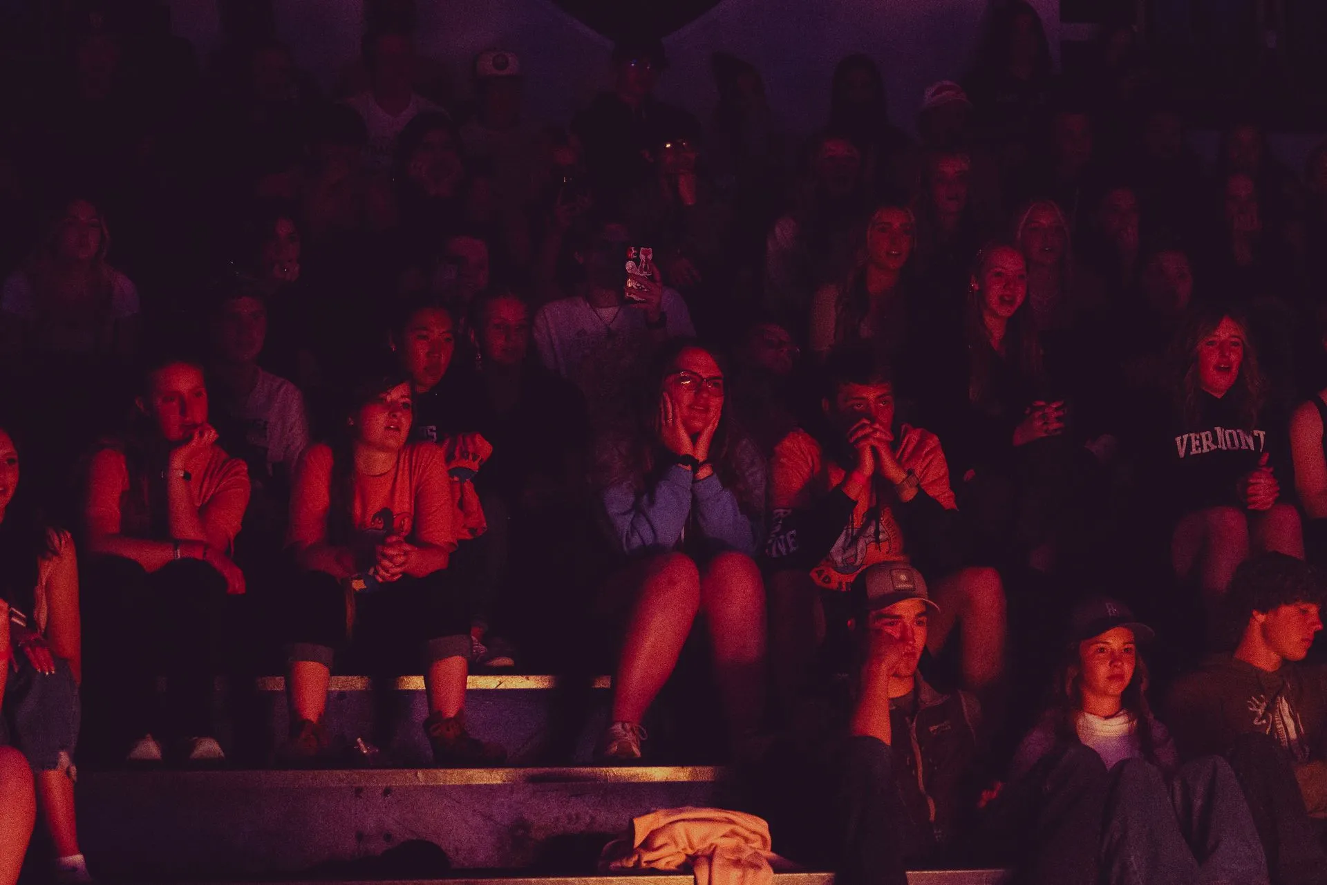 A large group of people are sitting in a dark room.