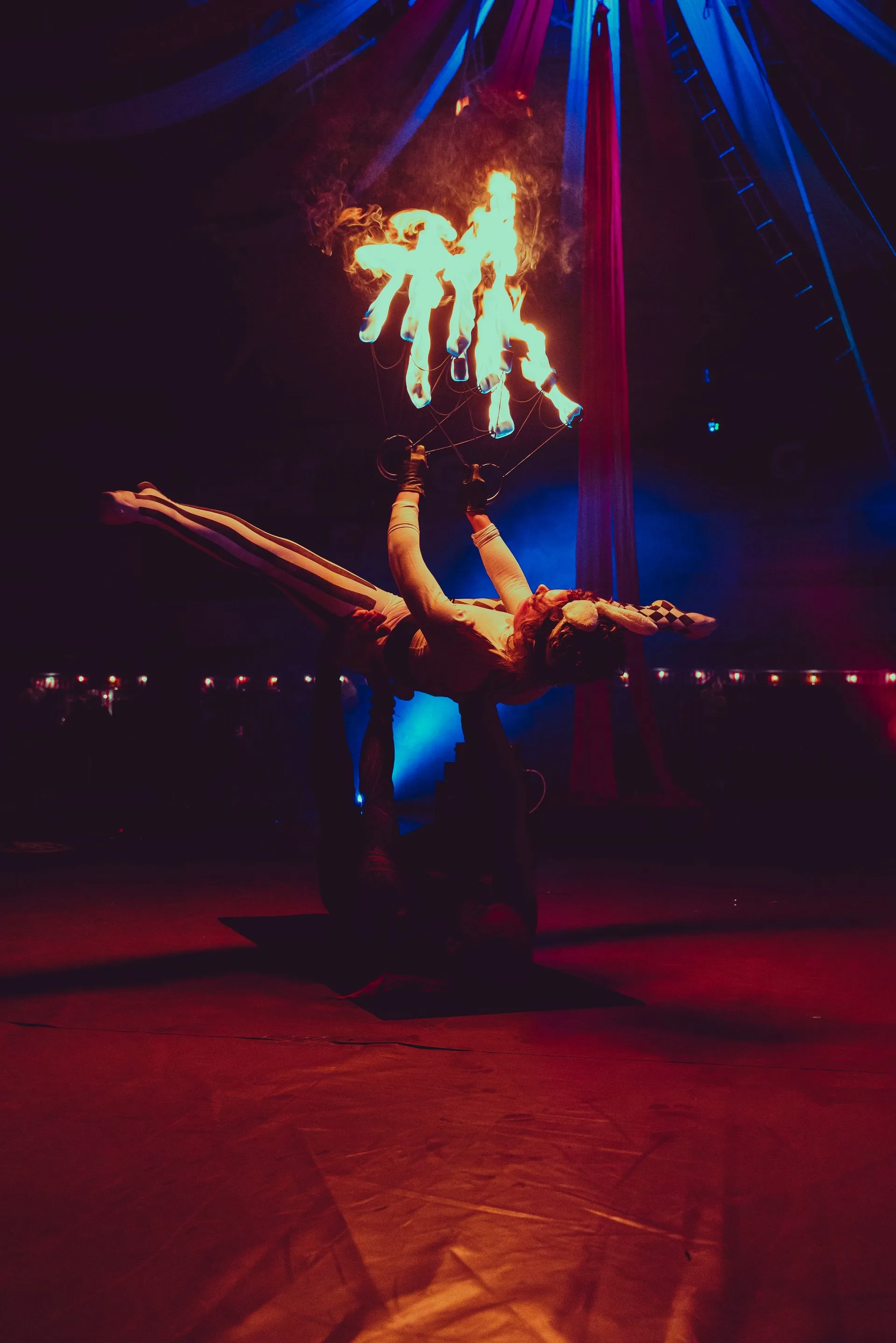 A woman is doing a handstand in front of a fire display.
