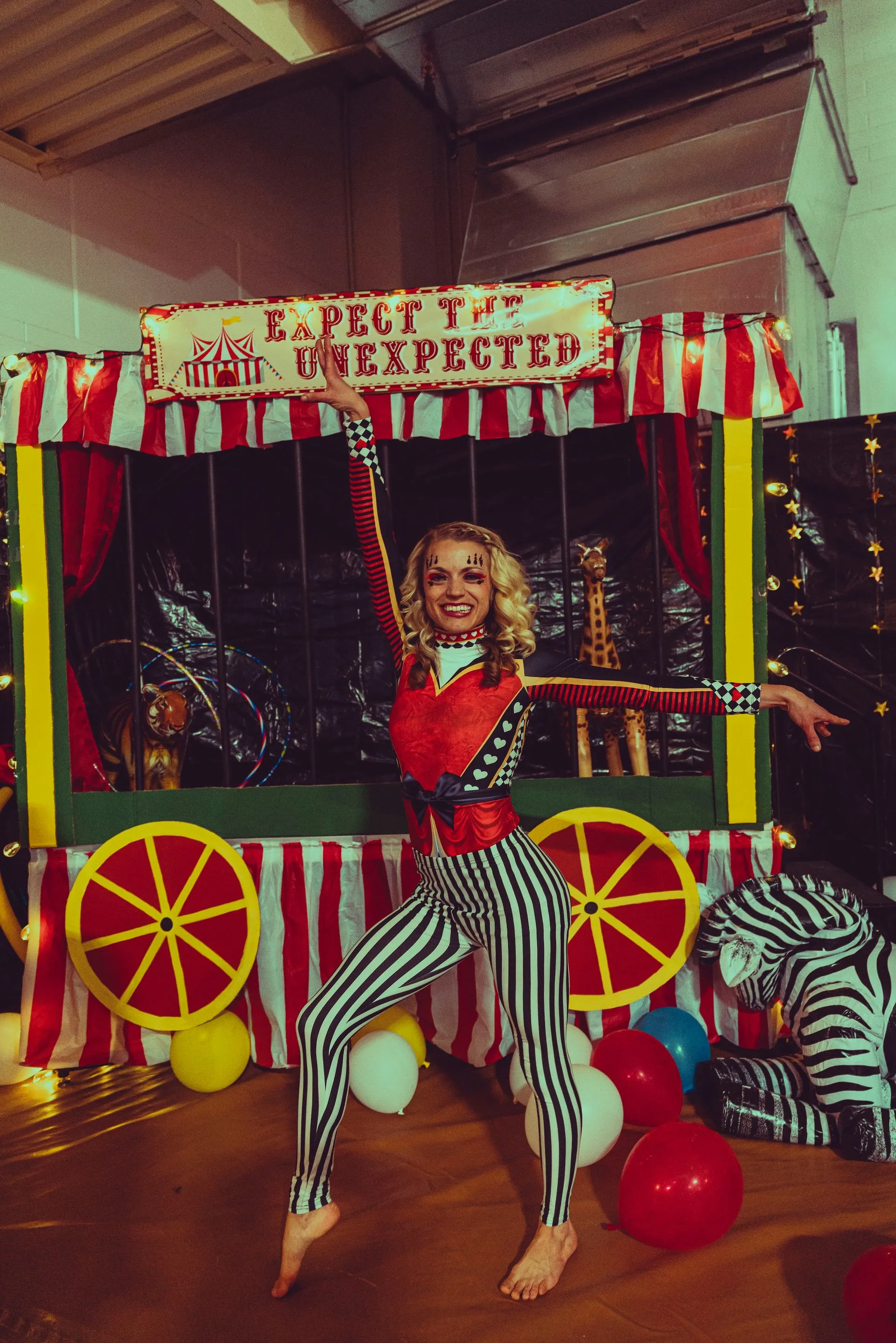 A woman in a circus costume is standing in front of a carnival booth.
