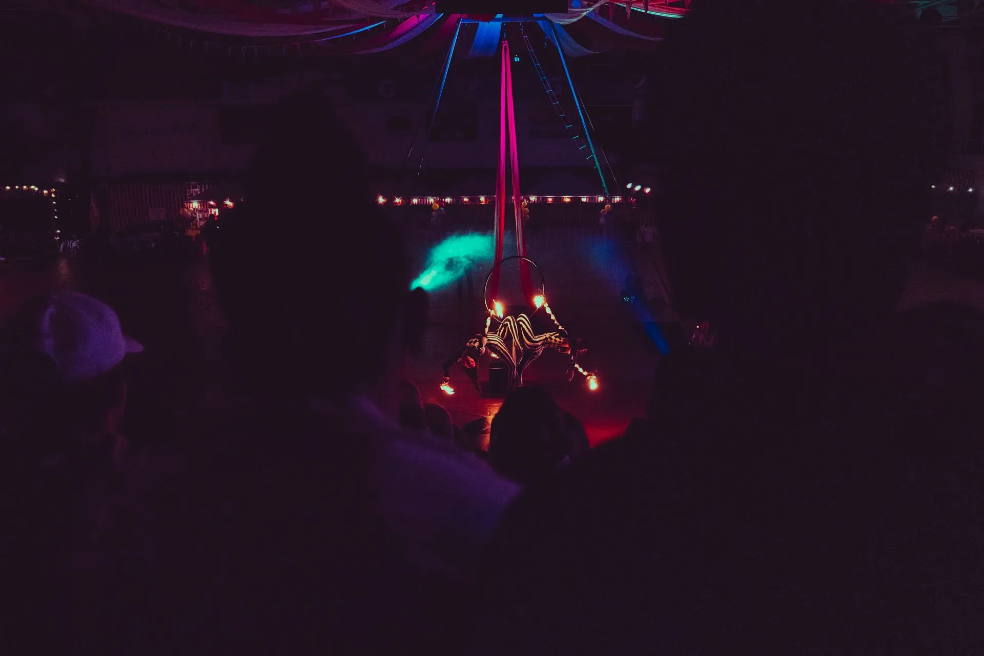 A group of people are dancing in a dark room at a party.