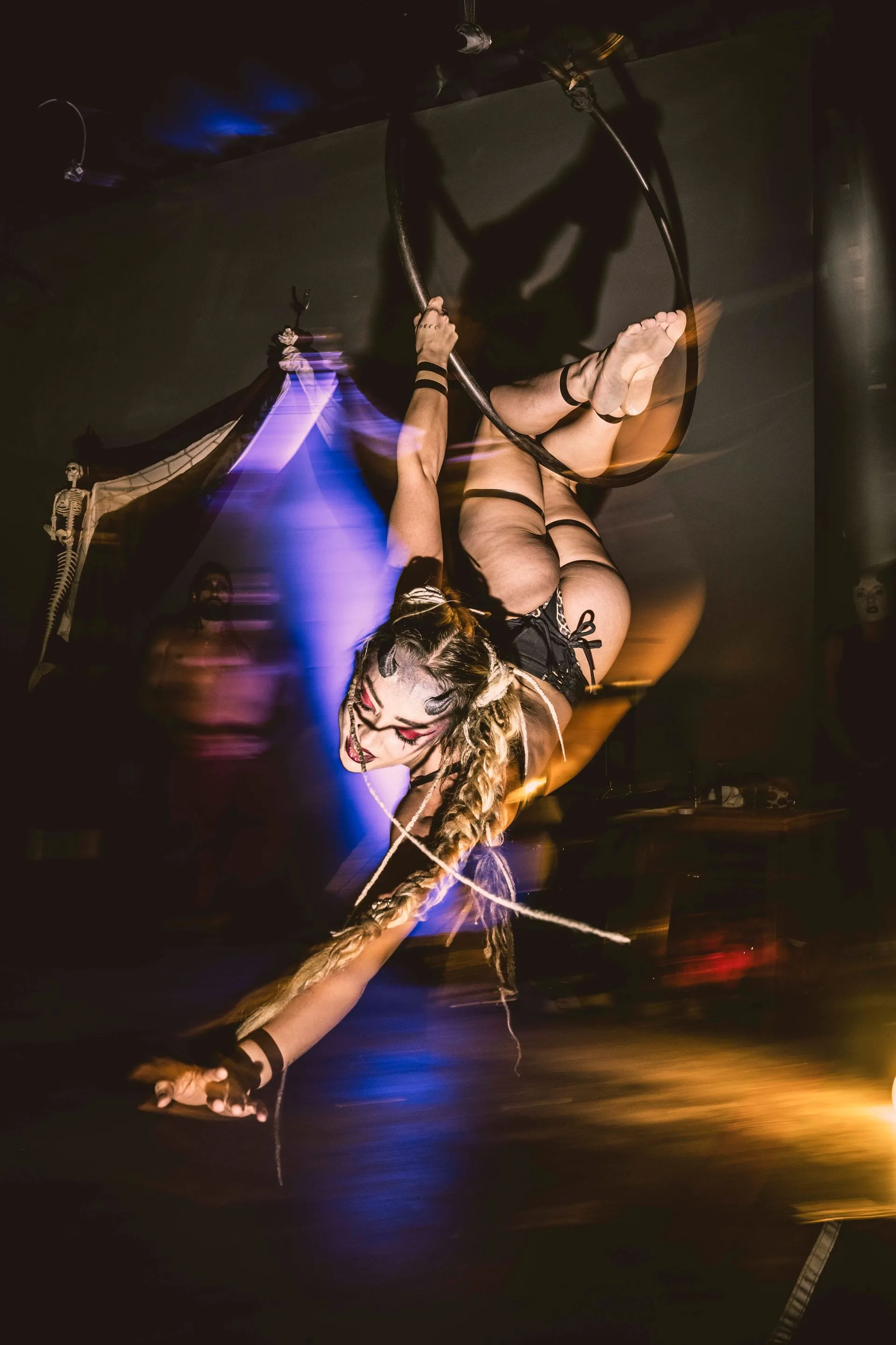 A woman is hanging upside down on an aerial hoop.