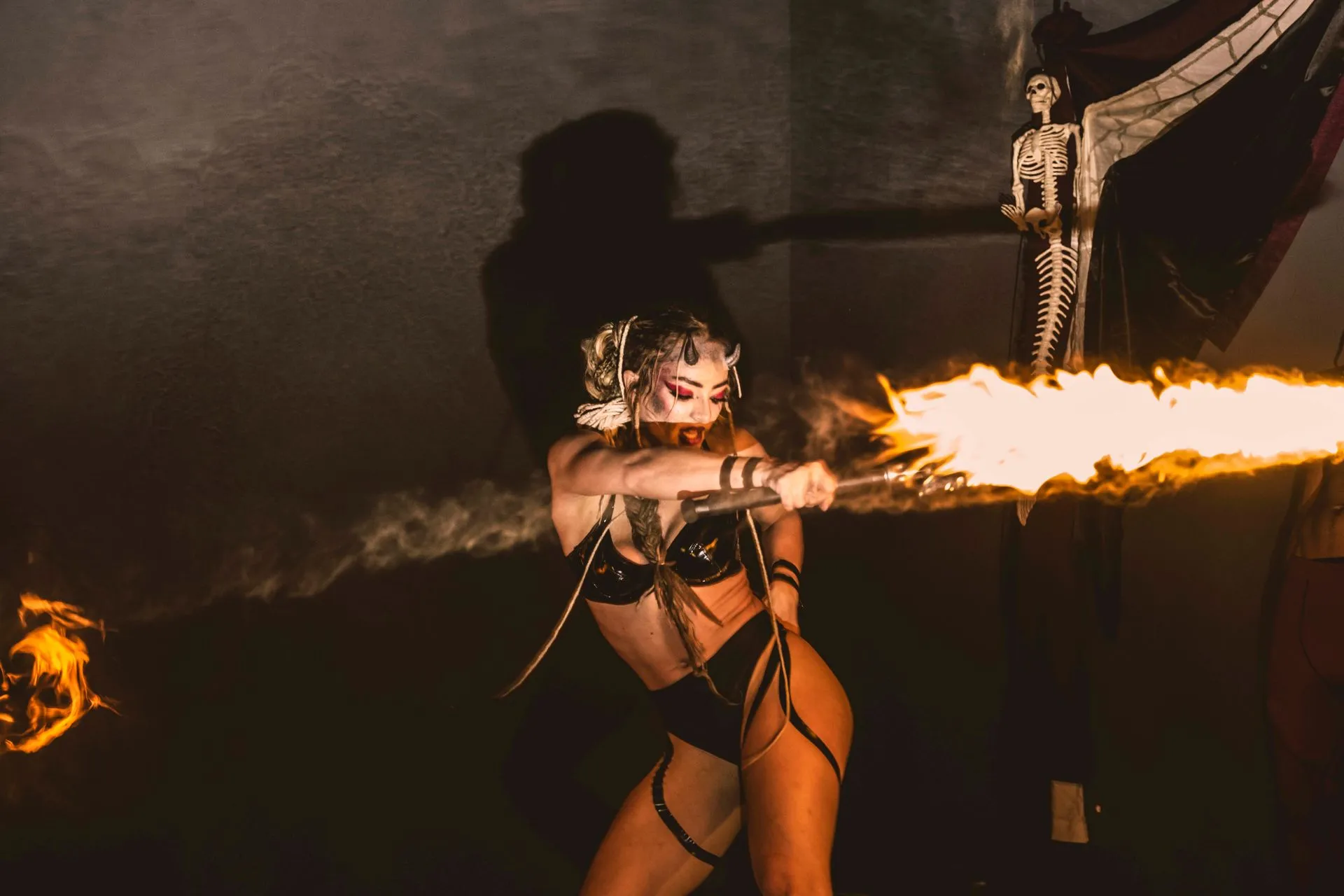 A woman in a costume is holding a torch with fire coming out of it.