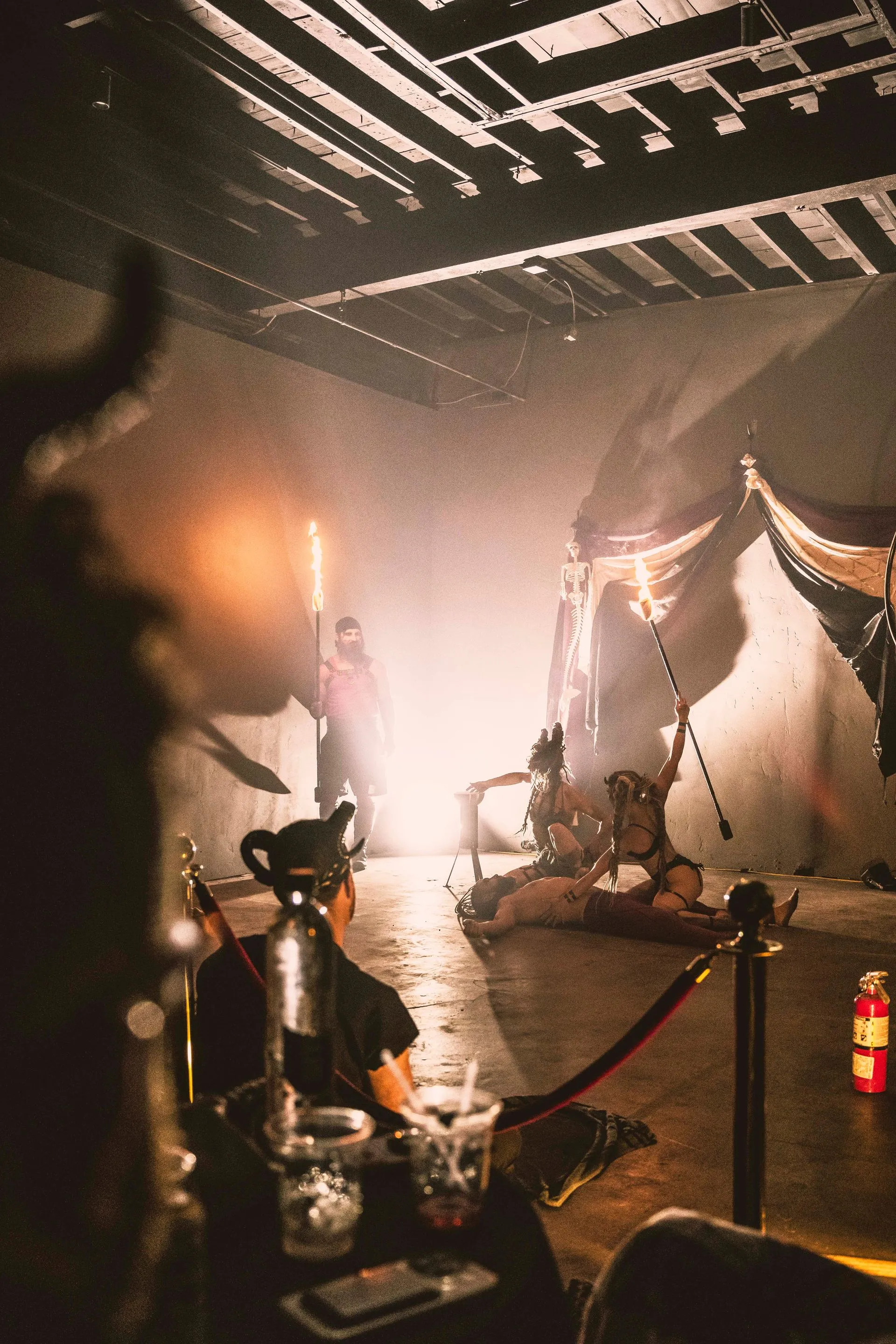 A man in a mask is sitting at a table in a dark room.