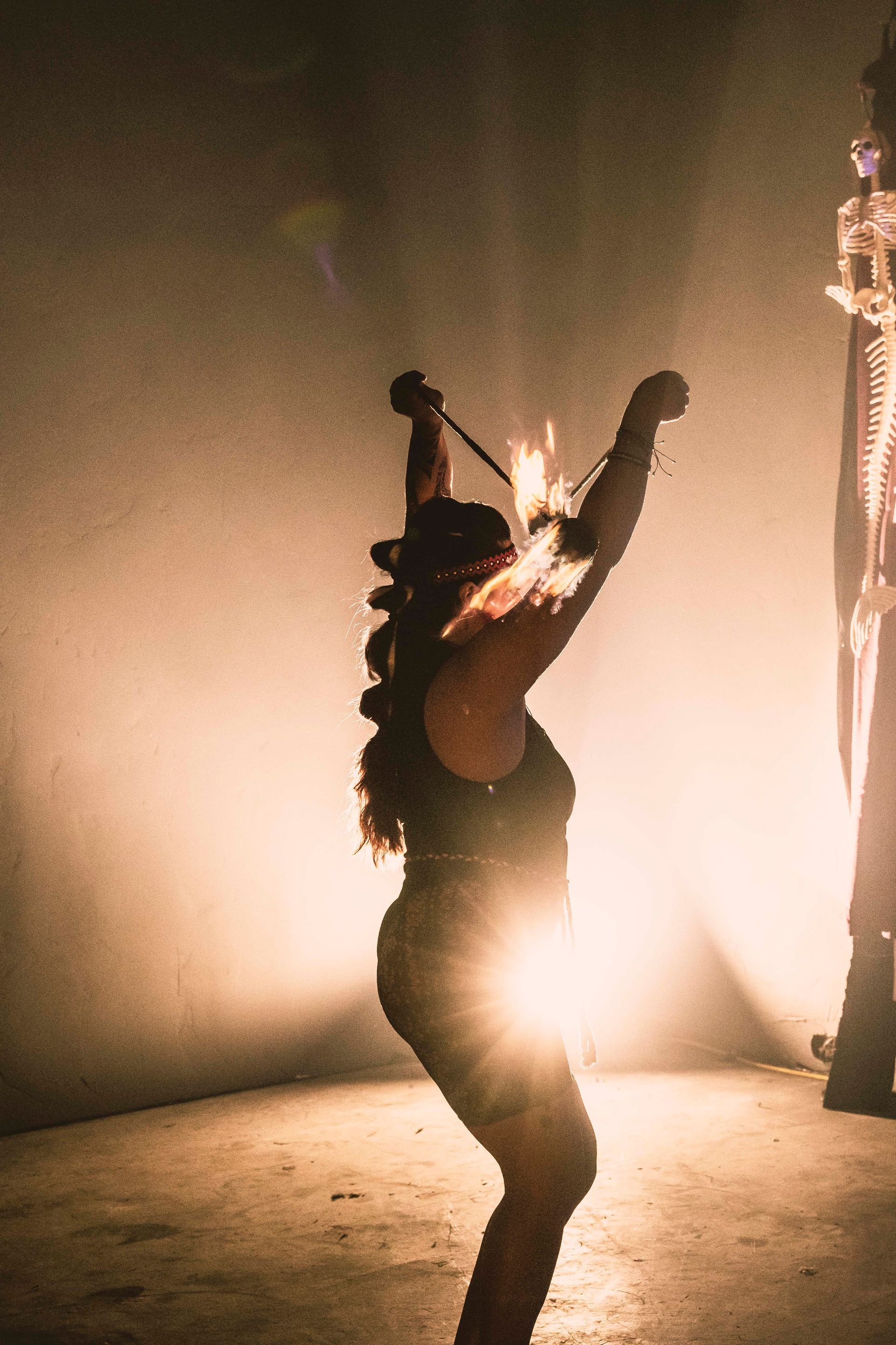 A woman performing with fire poi.