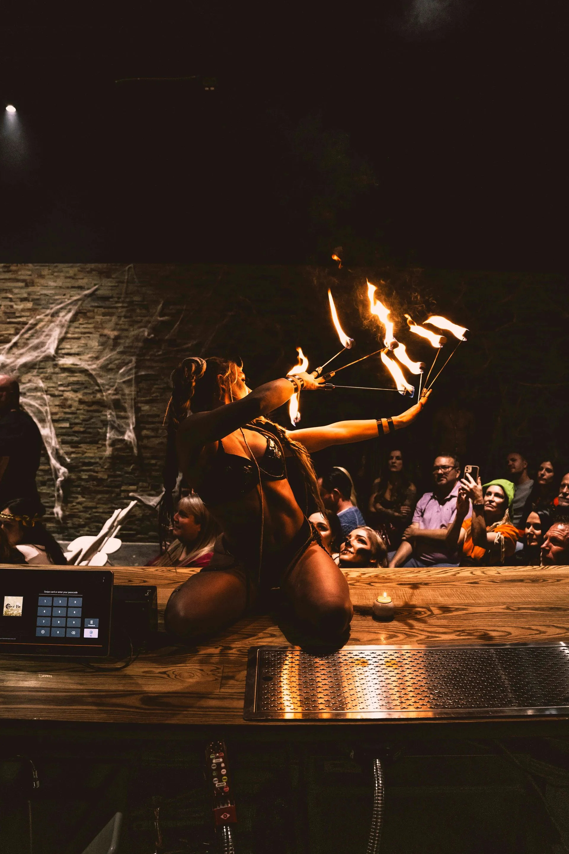 A woman is juggling fire in front of a crowd at a bar.