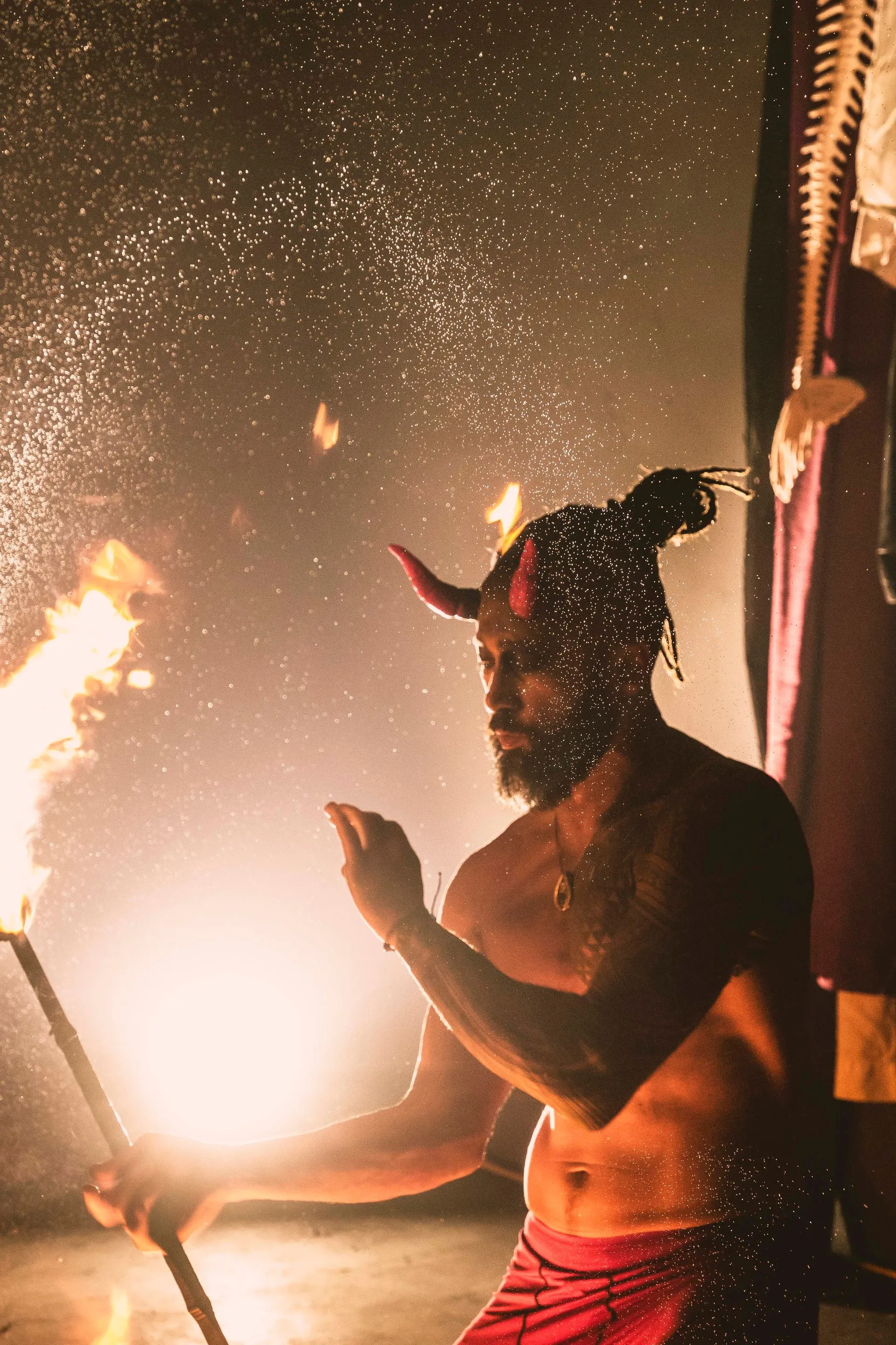 A man with horns is holding a torch in a dark room.