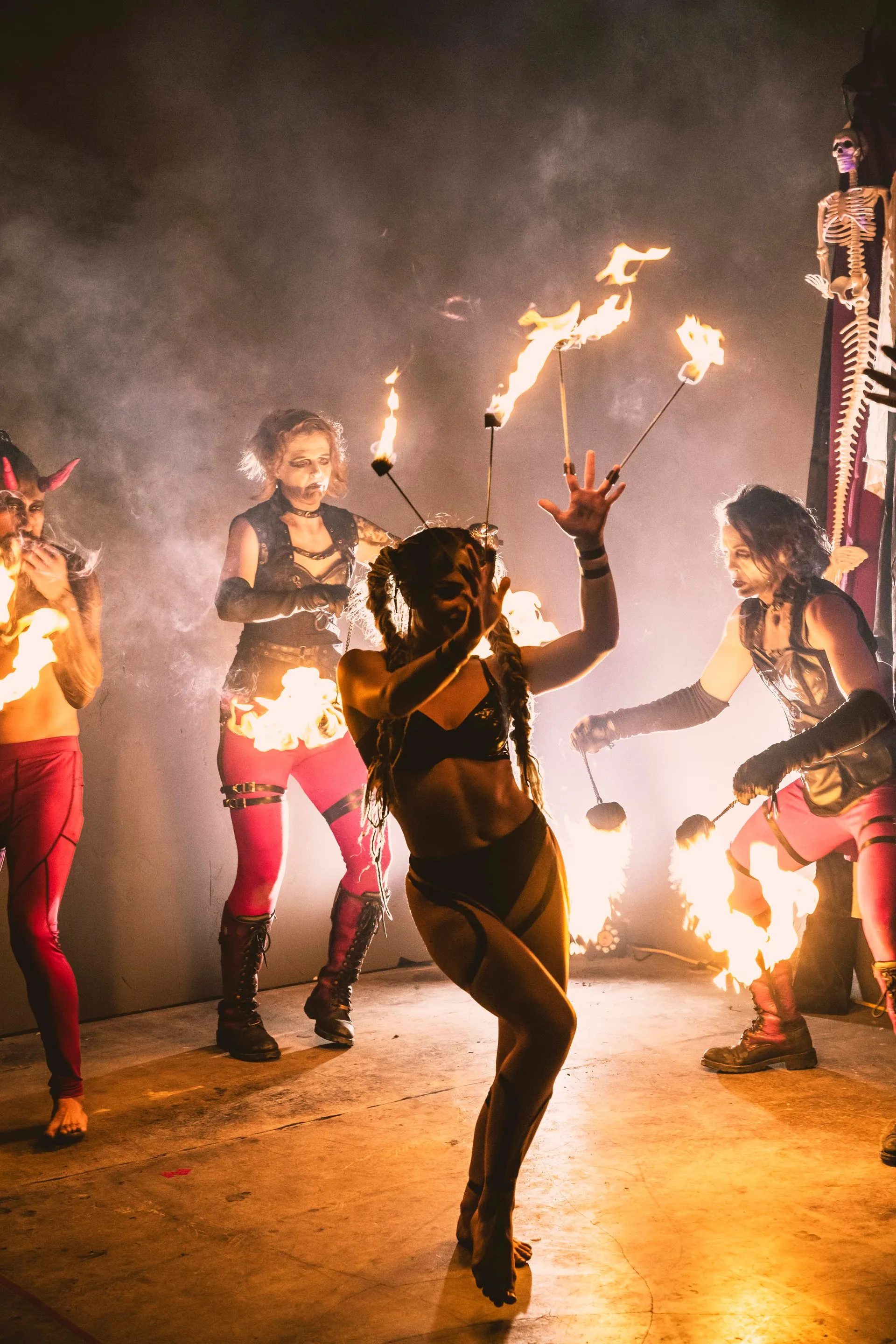 A group of people are dancing with fire in a dark room.