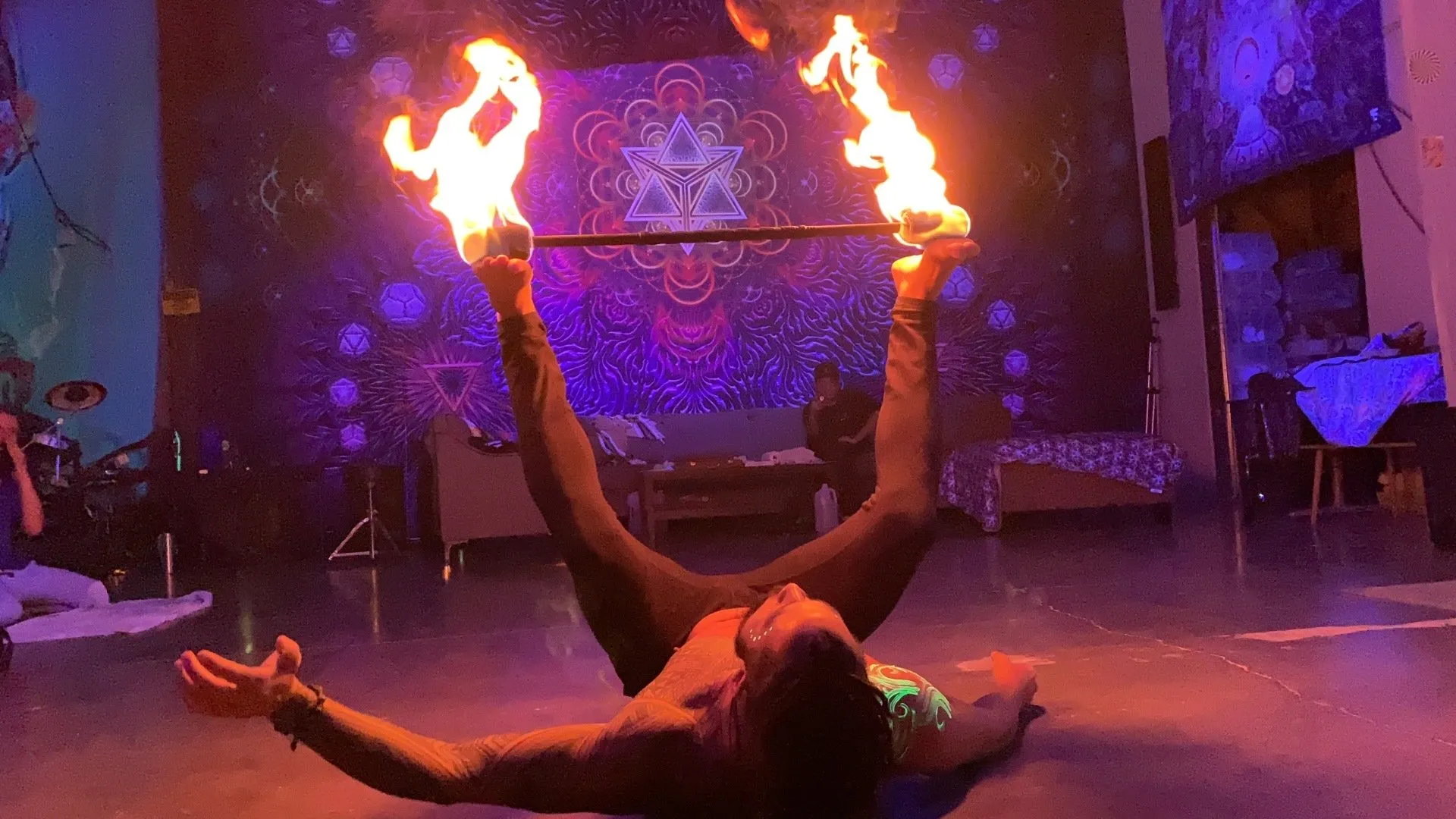 A man is laying on the floor holding a pair of fire sticks.