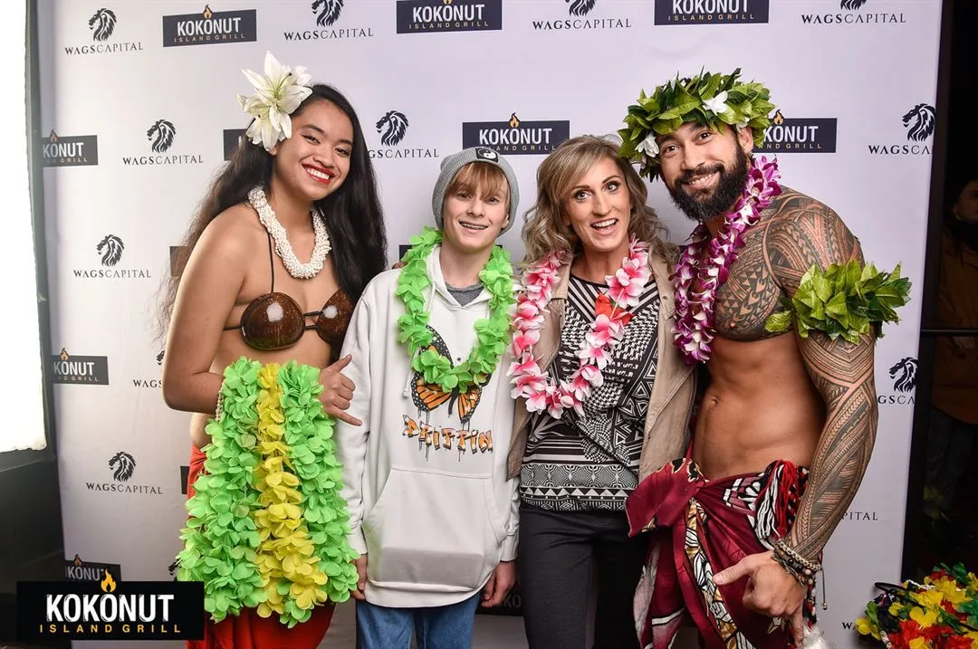 A group of people are posing for a picture in front of a coconut sign.