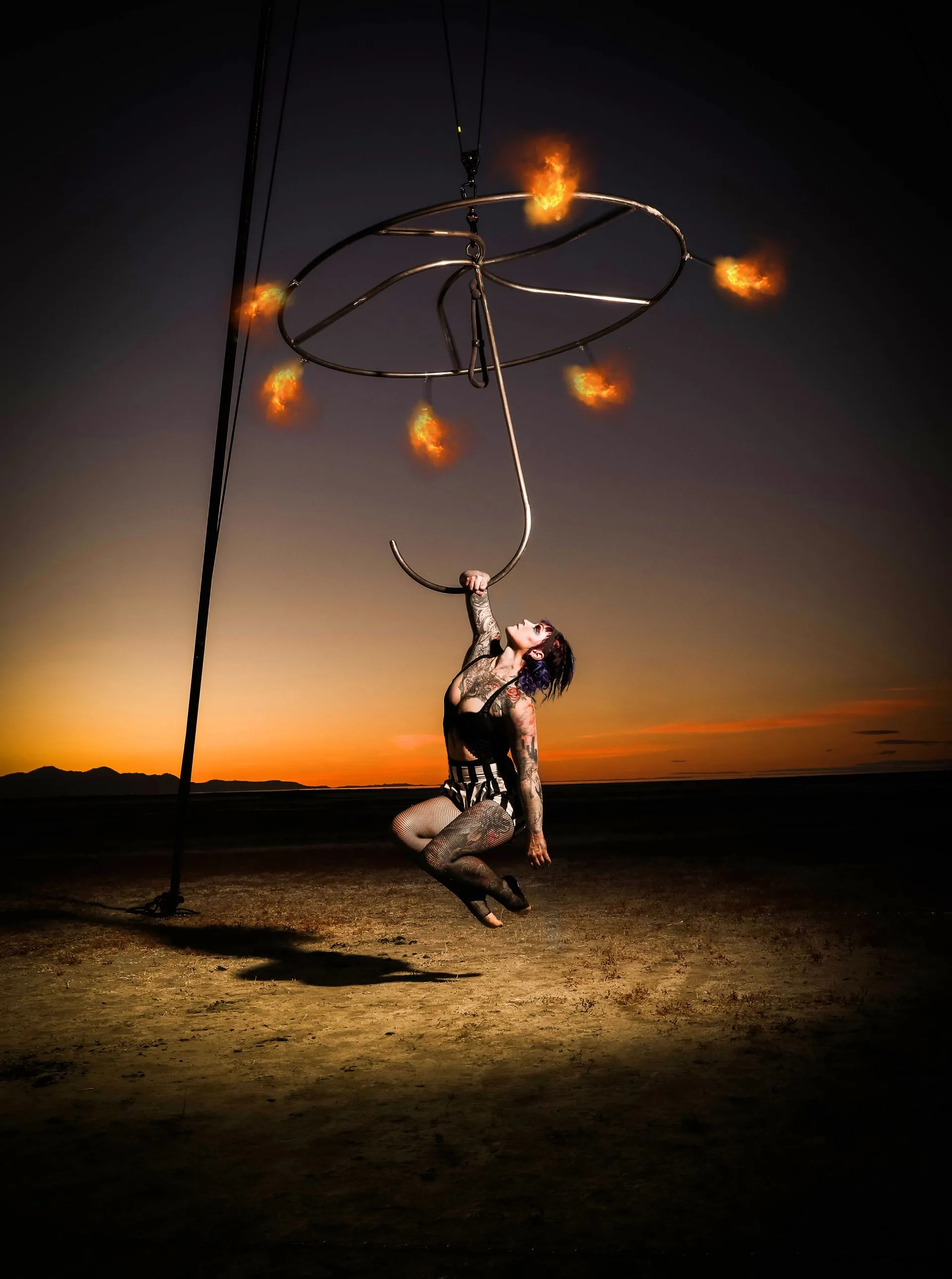 A woman is hanging from a rope with fire coming out of it.