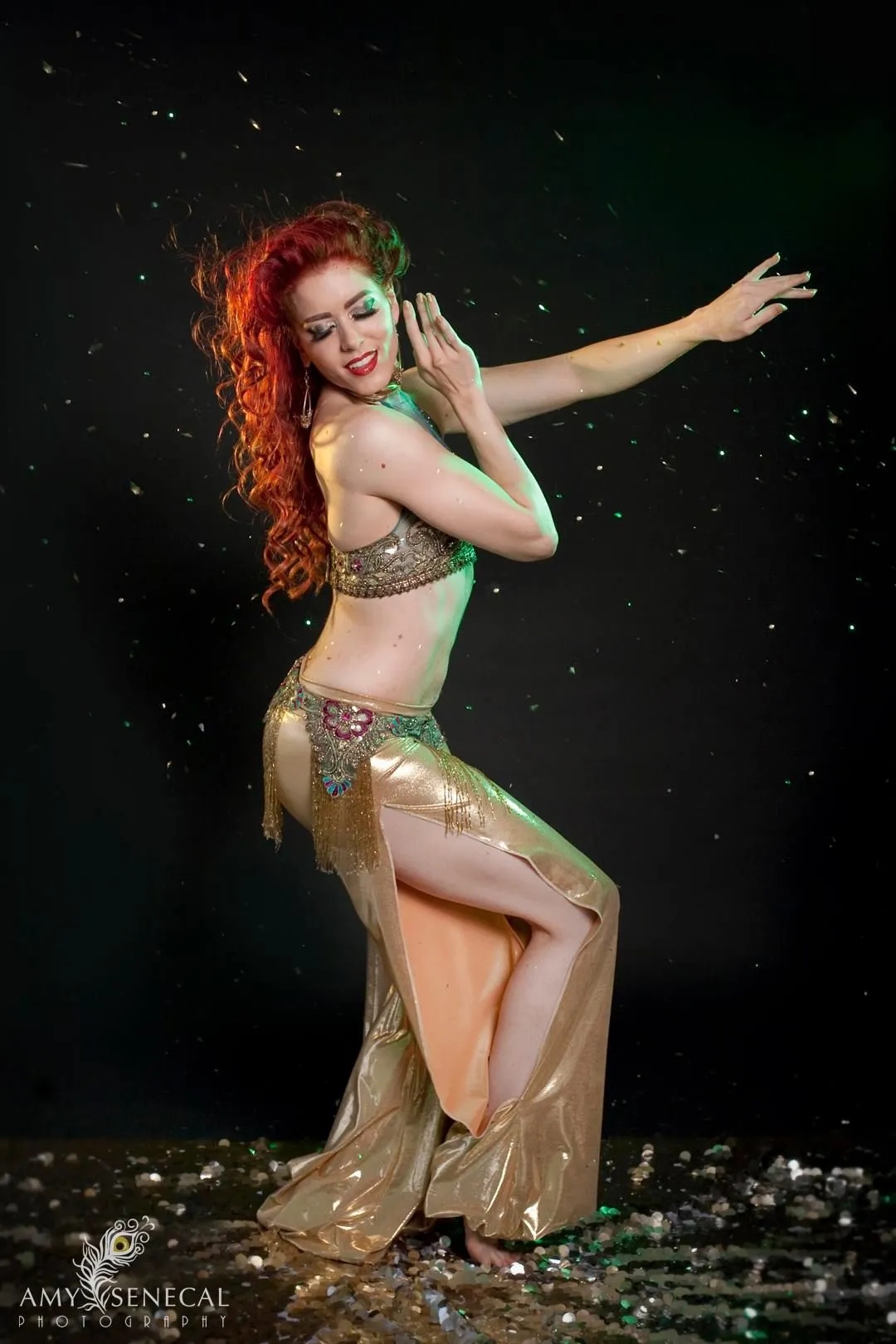 A woman in a belly dancer costume is dancing in the rain.