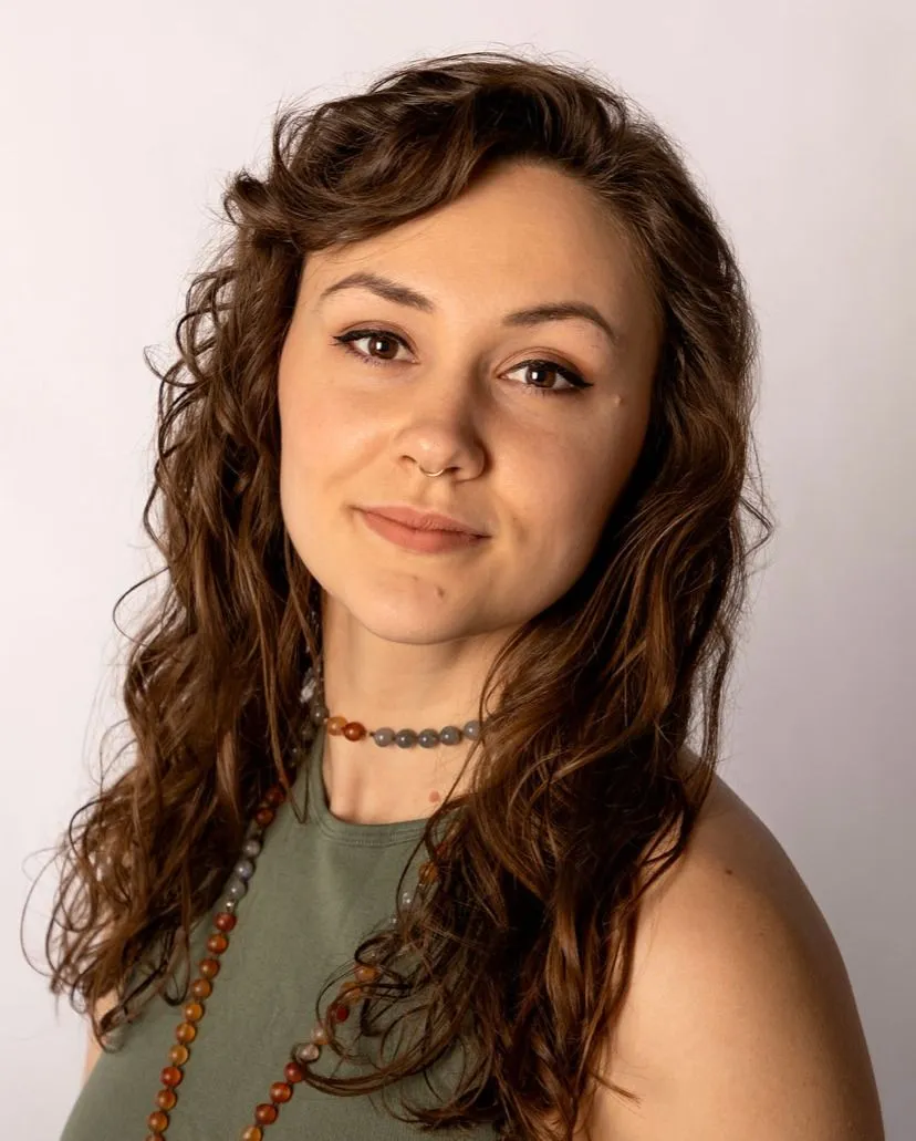 A woman with curly hair is wearing a choker and a green top.