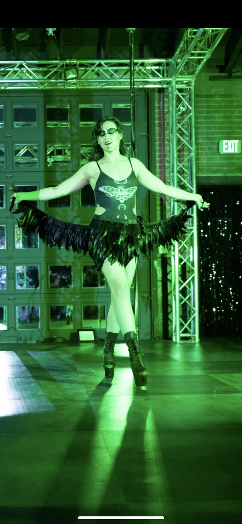 A woman is dancing in a dark room with green lights.