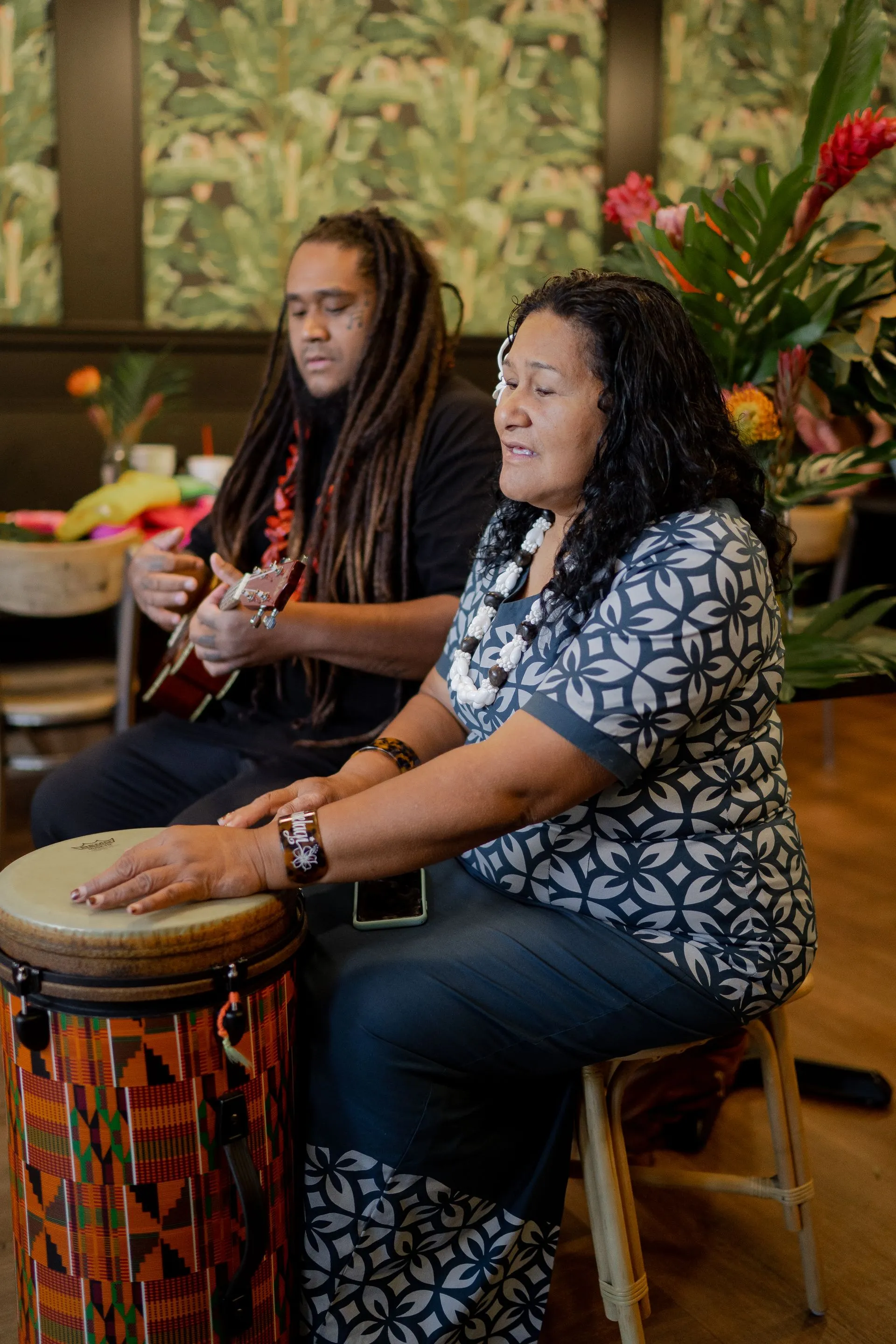 A man is playing a guitar and a woman is playing a drum.