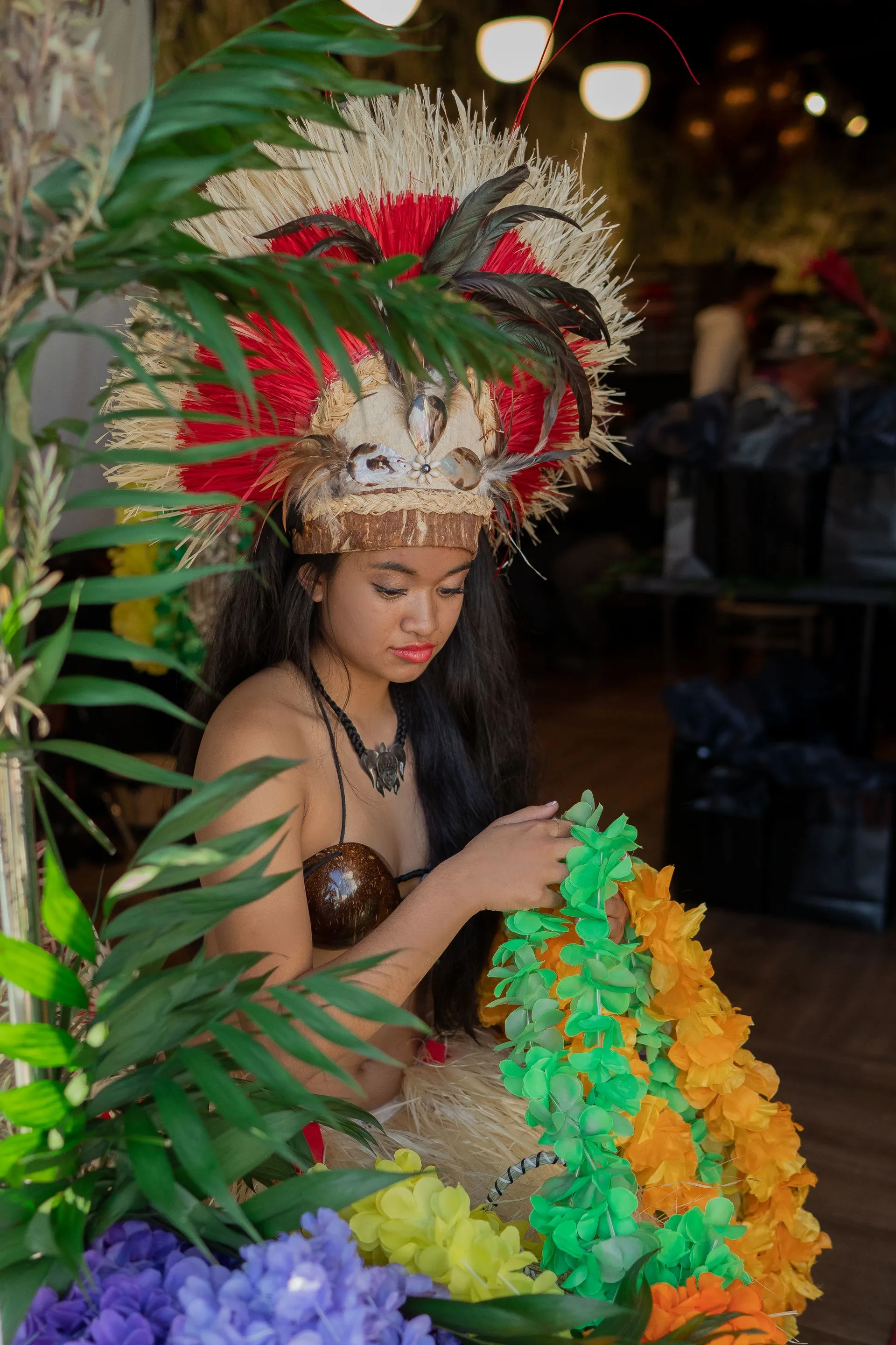A woman in a Tahitian outfit is passing out leis.