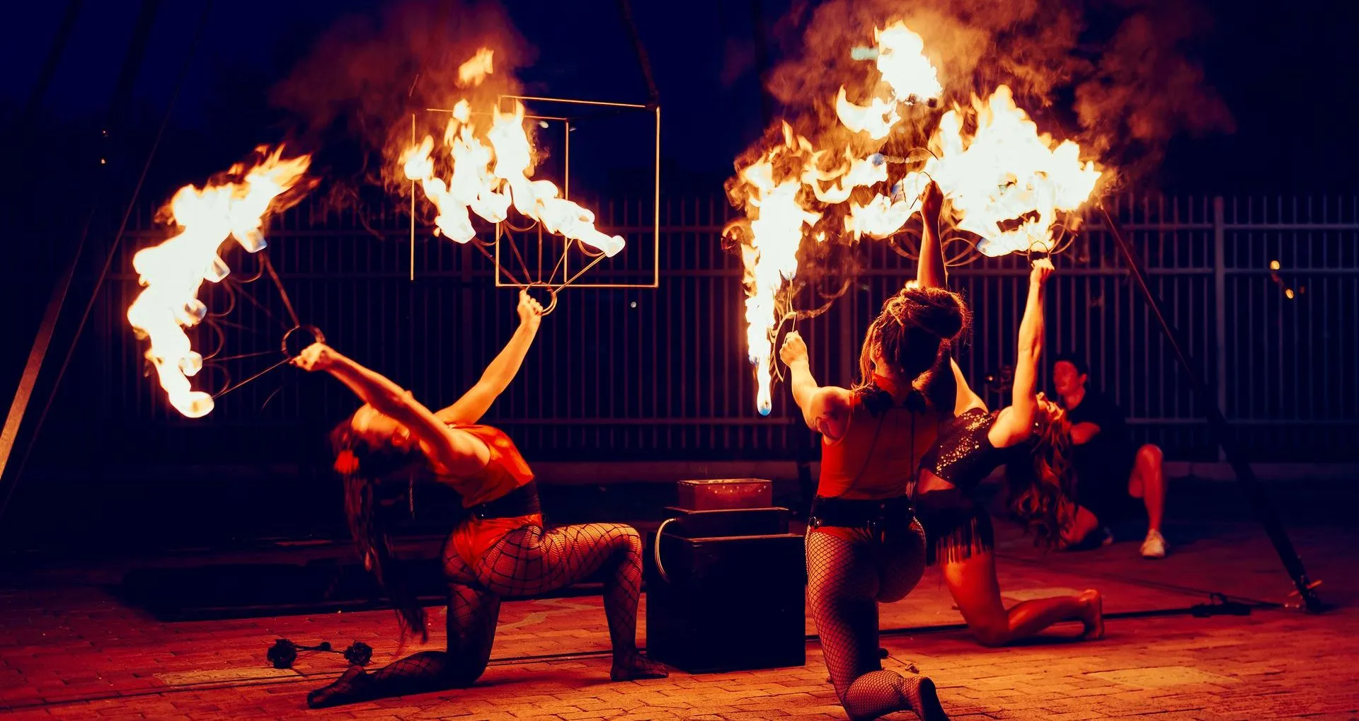 3 women dancing with fire in a circus show.