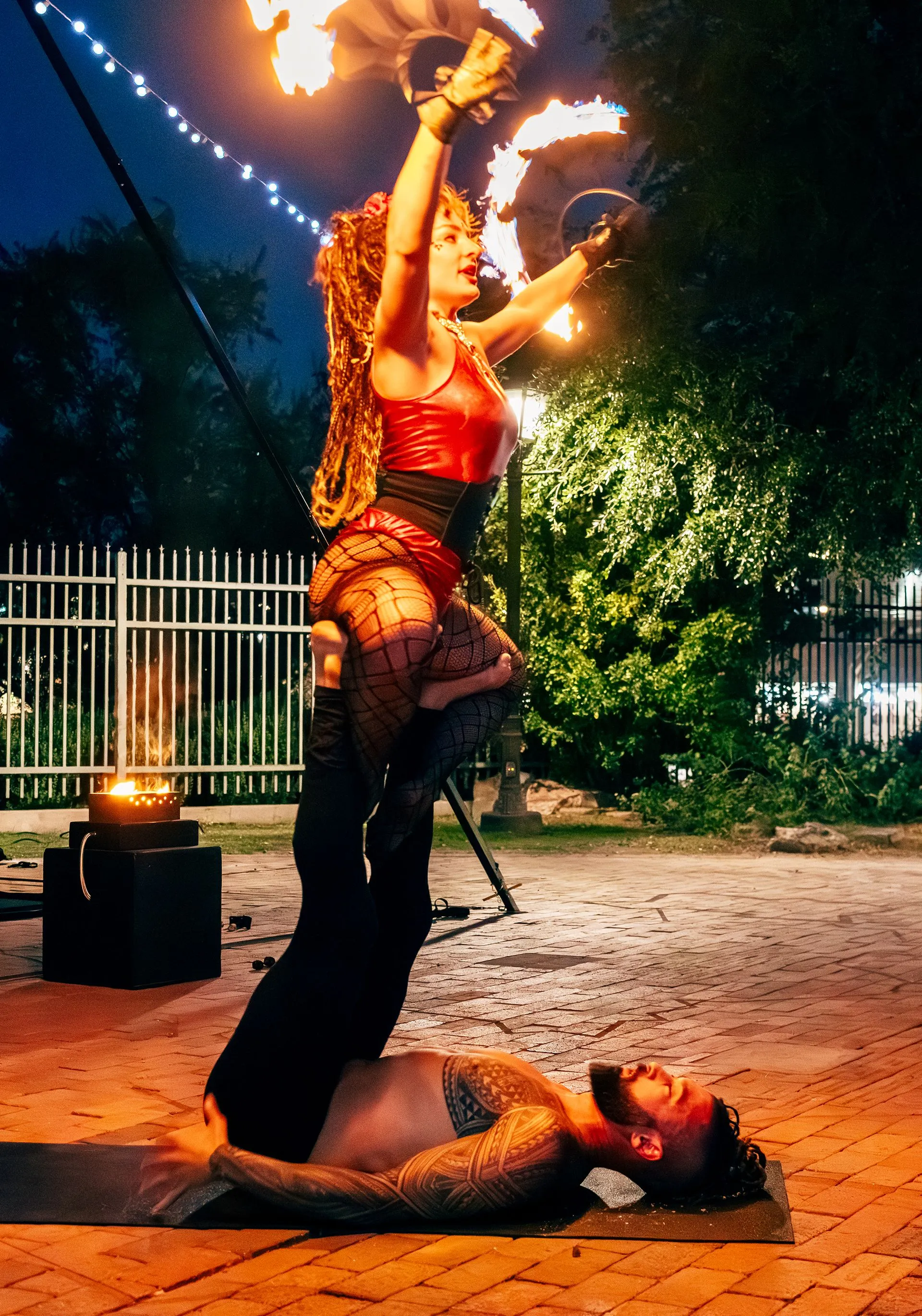 A woman is carrying a man on her shoulders while holding a fire torch.