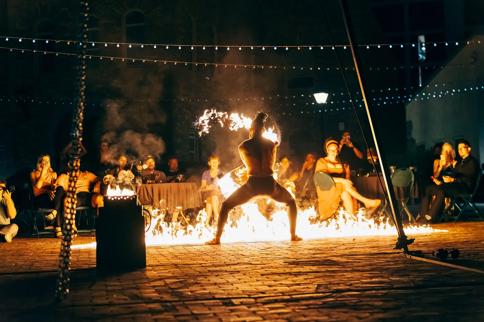 A man is standing in front of a fire at night.