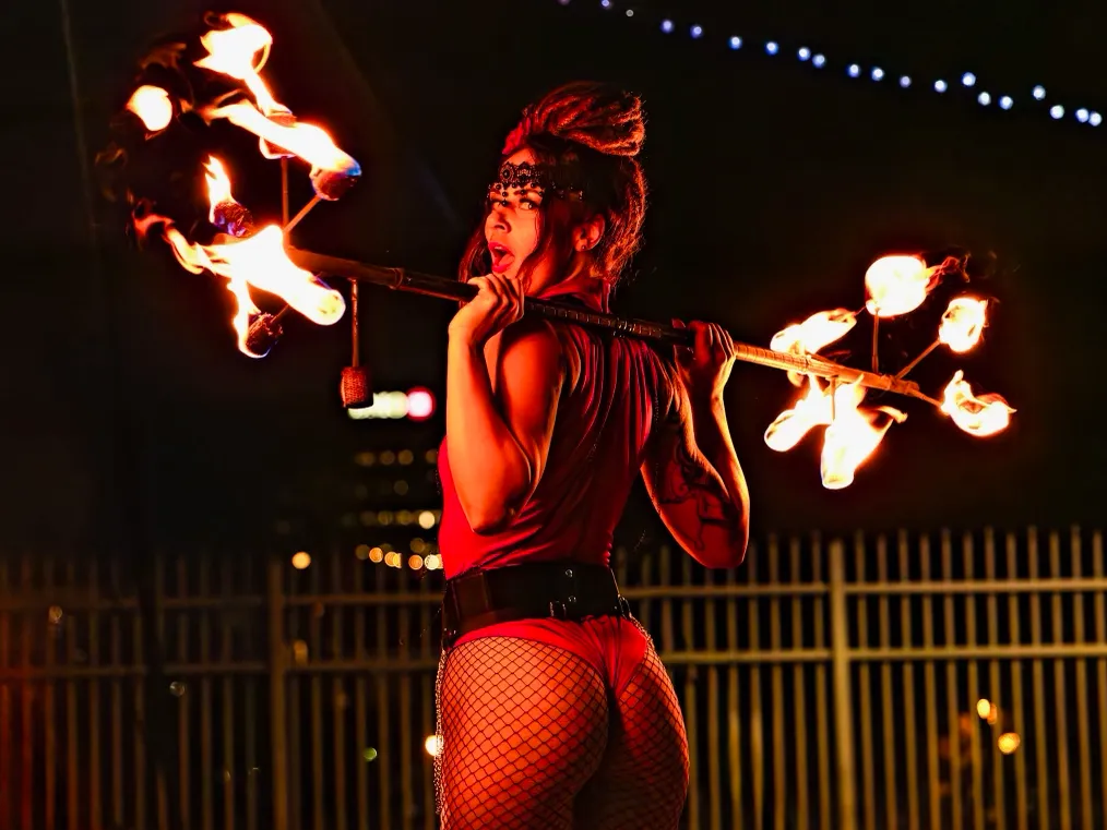 A woman in a red outfit is holding a stick of fire.