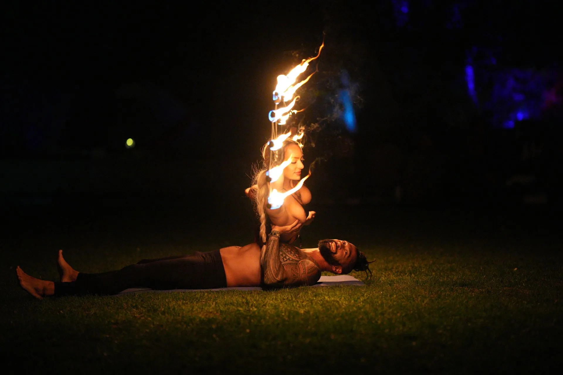 A man is laying on a yoga mat with fire coming out of his mouth.