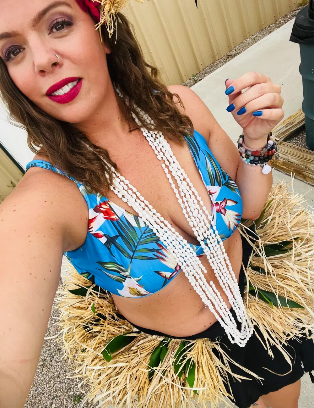 A woman in a bikini and a hula skirt is taking a selfie