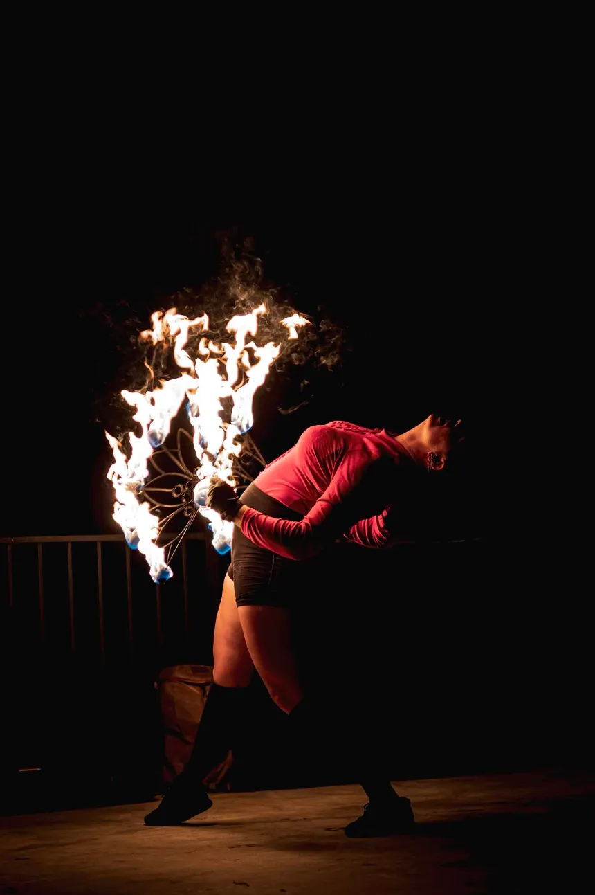 A woman is performing a fire show in the dark.