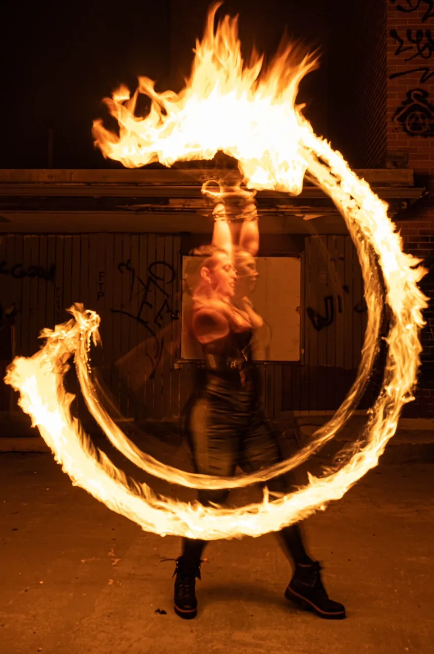A woman is spinning a circle of fire in her hands.
