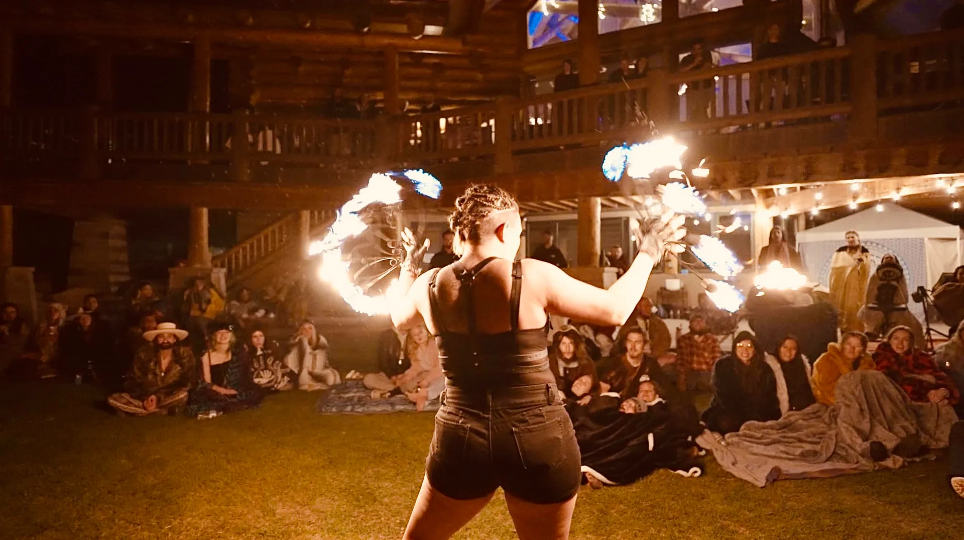 A woman is performing a fire show in front of a crowd of people.