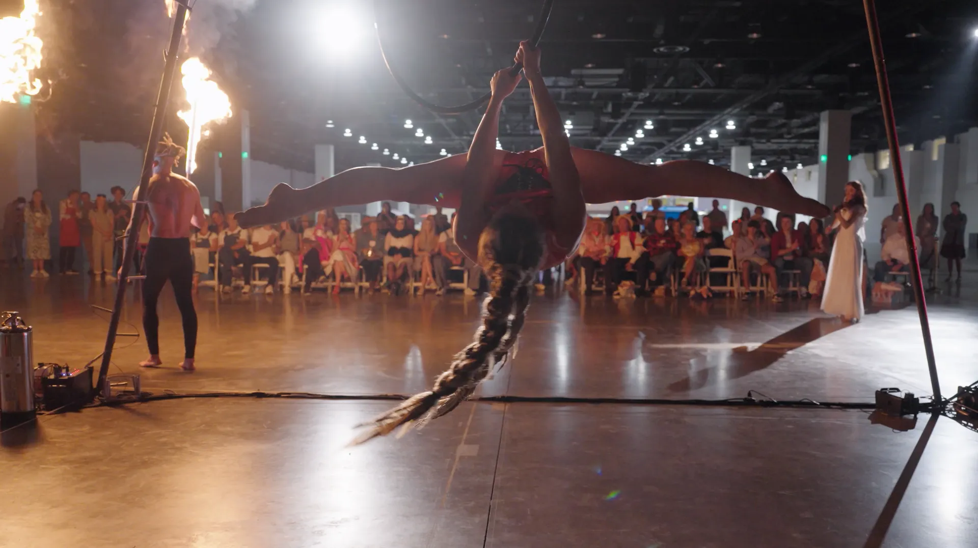 A woman is doing aerial acrobatics in front of a crowd of people.