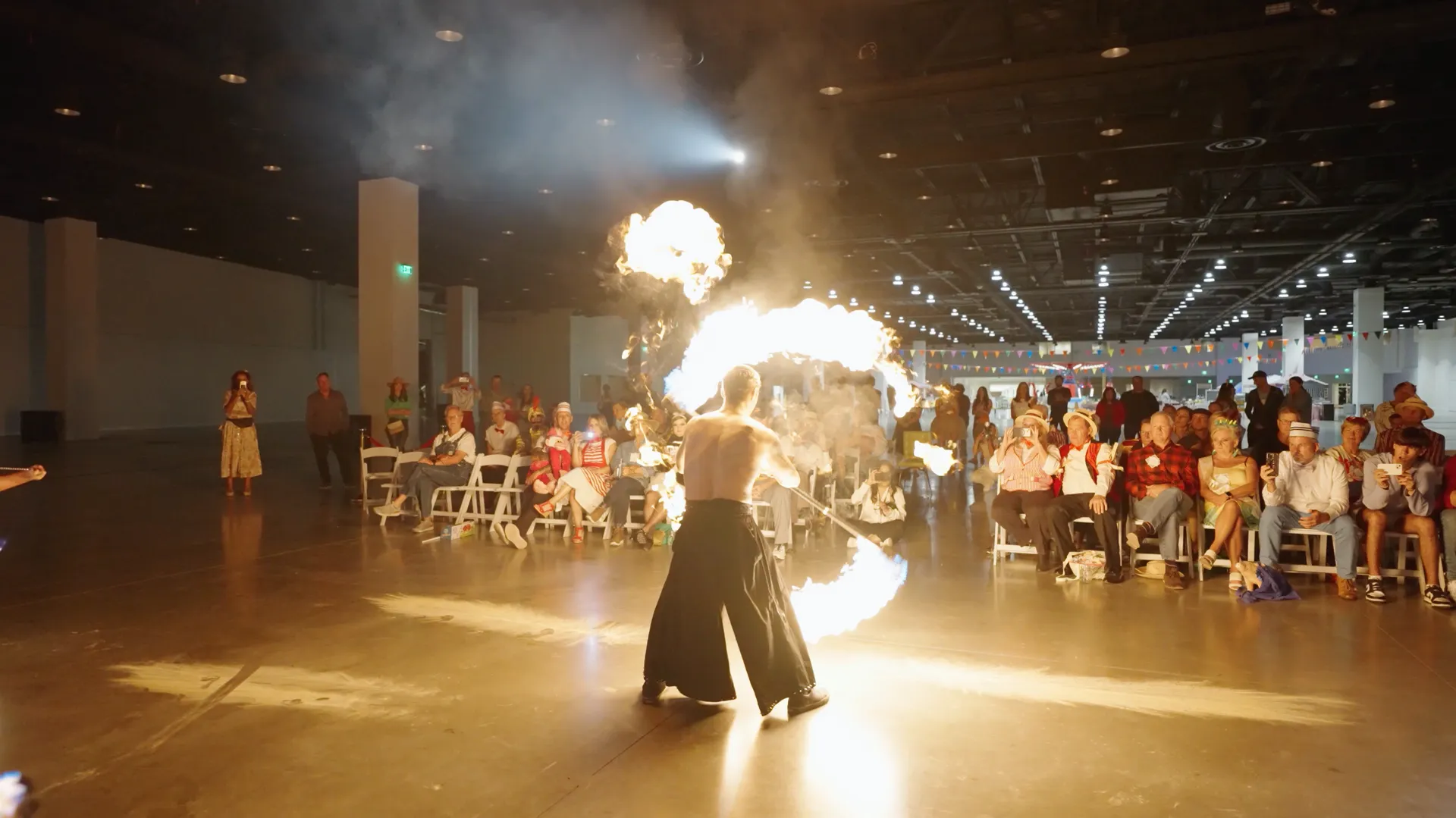 A man is holding a fireball in front of a crowd of people.