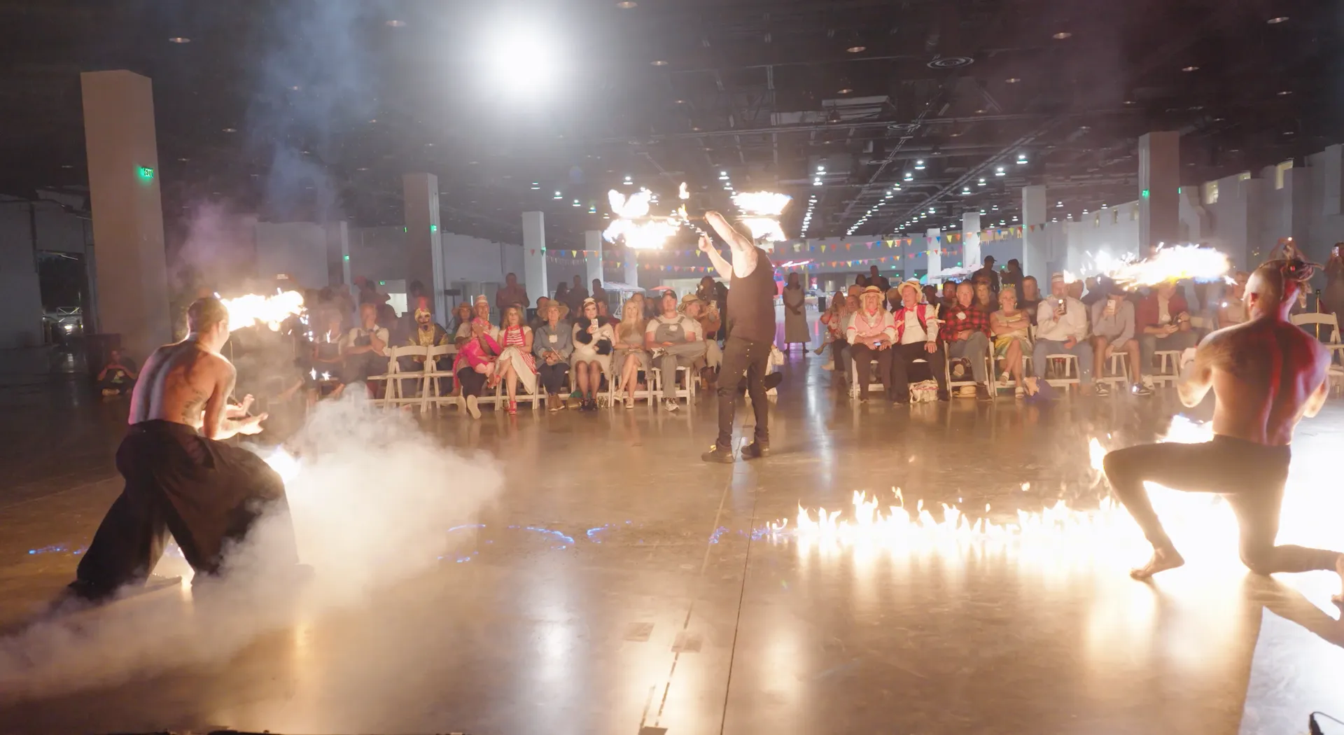 A group of people are dancing with fire in front of a crowd.