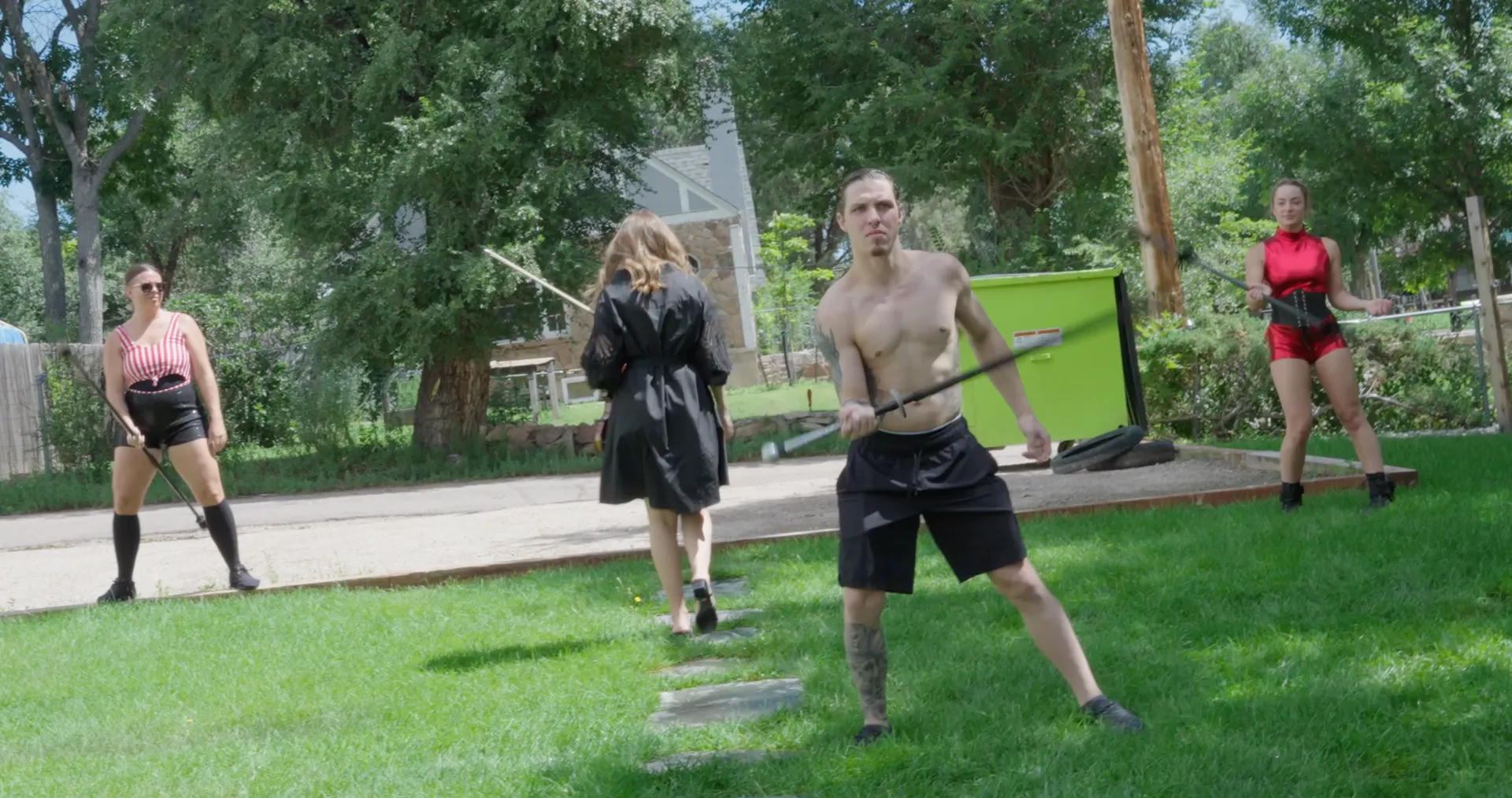 A group of people are standing on top of a lush green field holding swords.