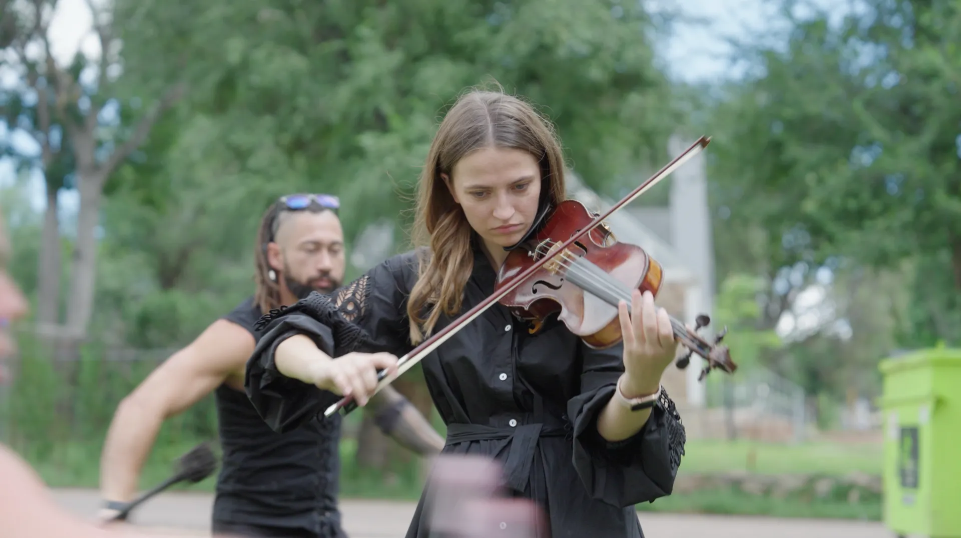 A woman is playing a violin in front of a man.