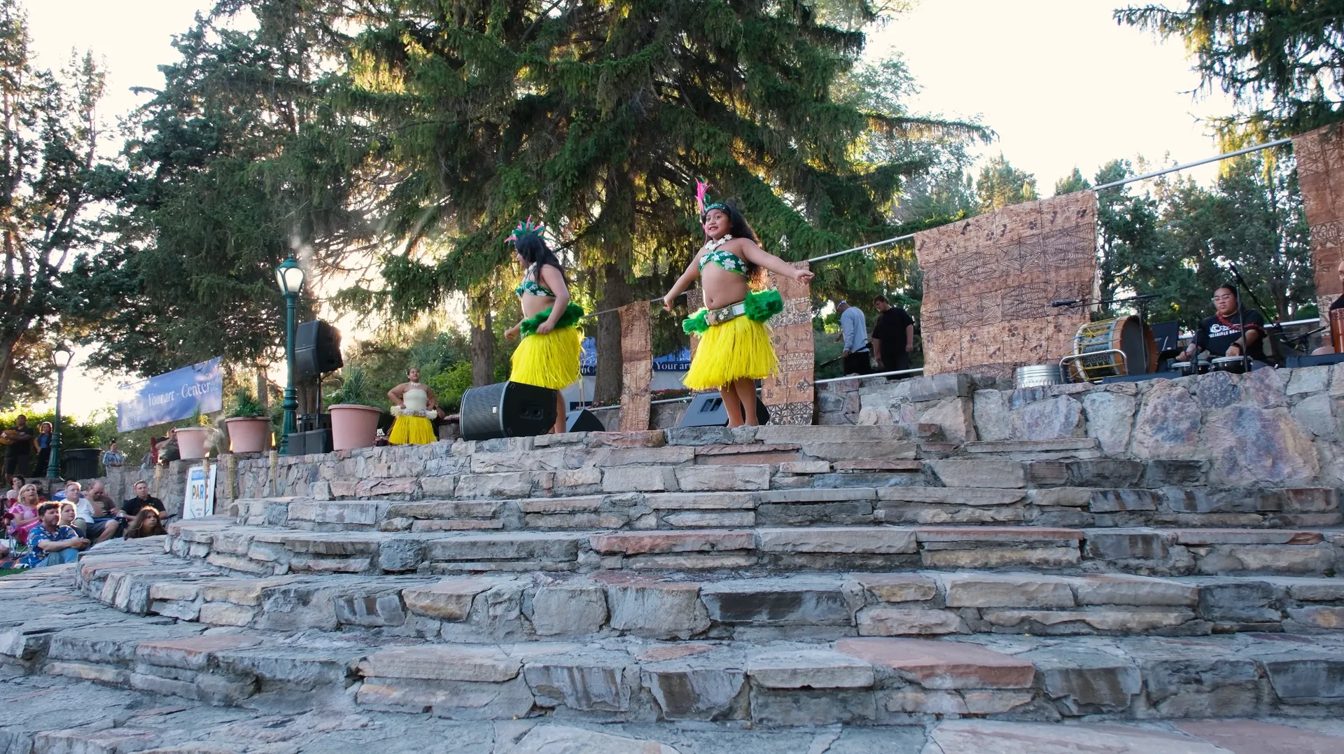 Two hula dancers are performing on a stone stage